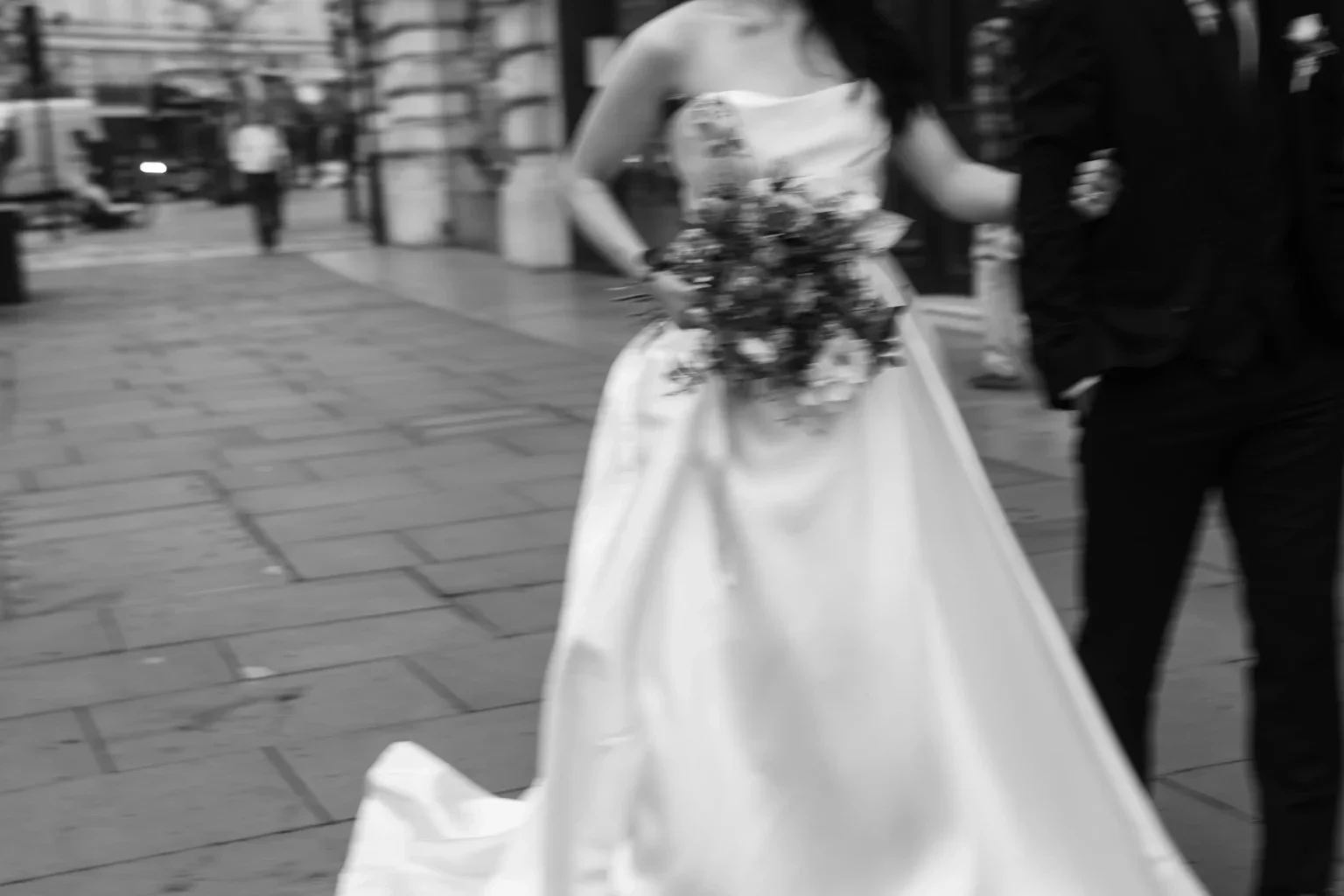 ウェディングドレスを着た花嫁とその隣の人が結婚式の準備をしている都市の通りの光景。