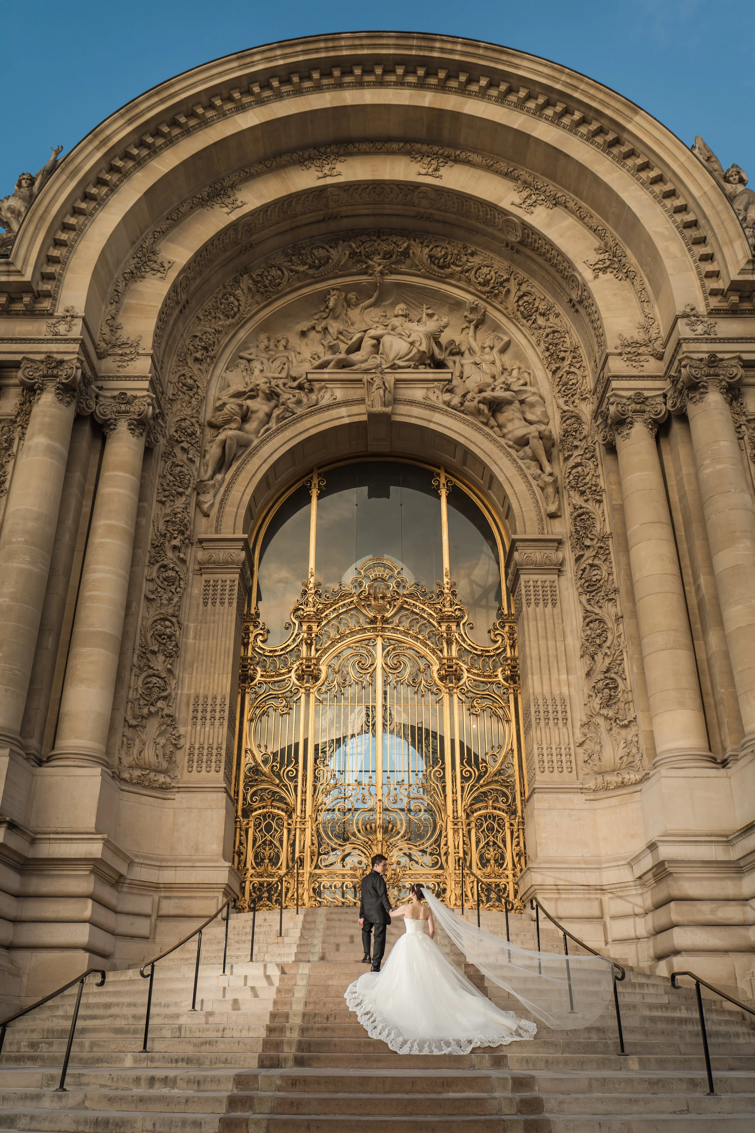 結婚式の新郎新婦が大きな金色の門の前で写真を撮っている