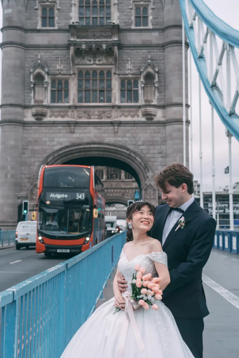 ロンドンのタワーブリッジの前で結婚式をしたカップルが笑顔で写真を撮っている