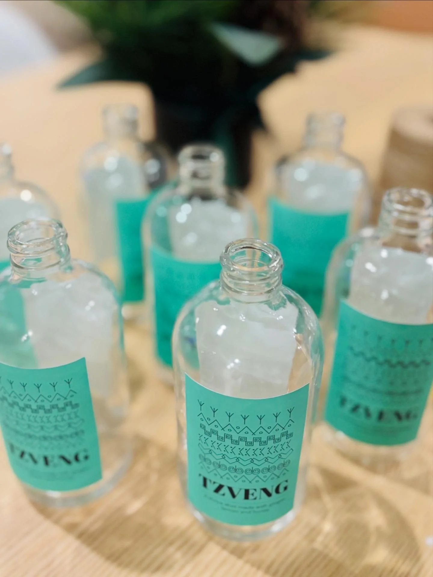Multiple small clear bottles with Tzveng labels showing our bottling process.