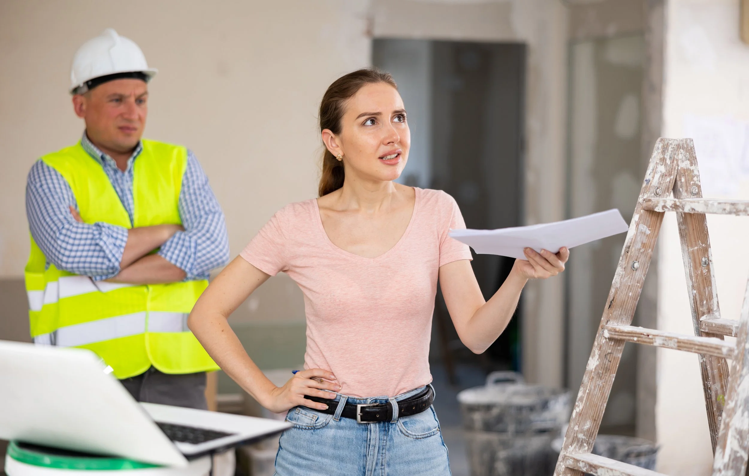 A female designer confronting a problem on a job site as contractor looks on
