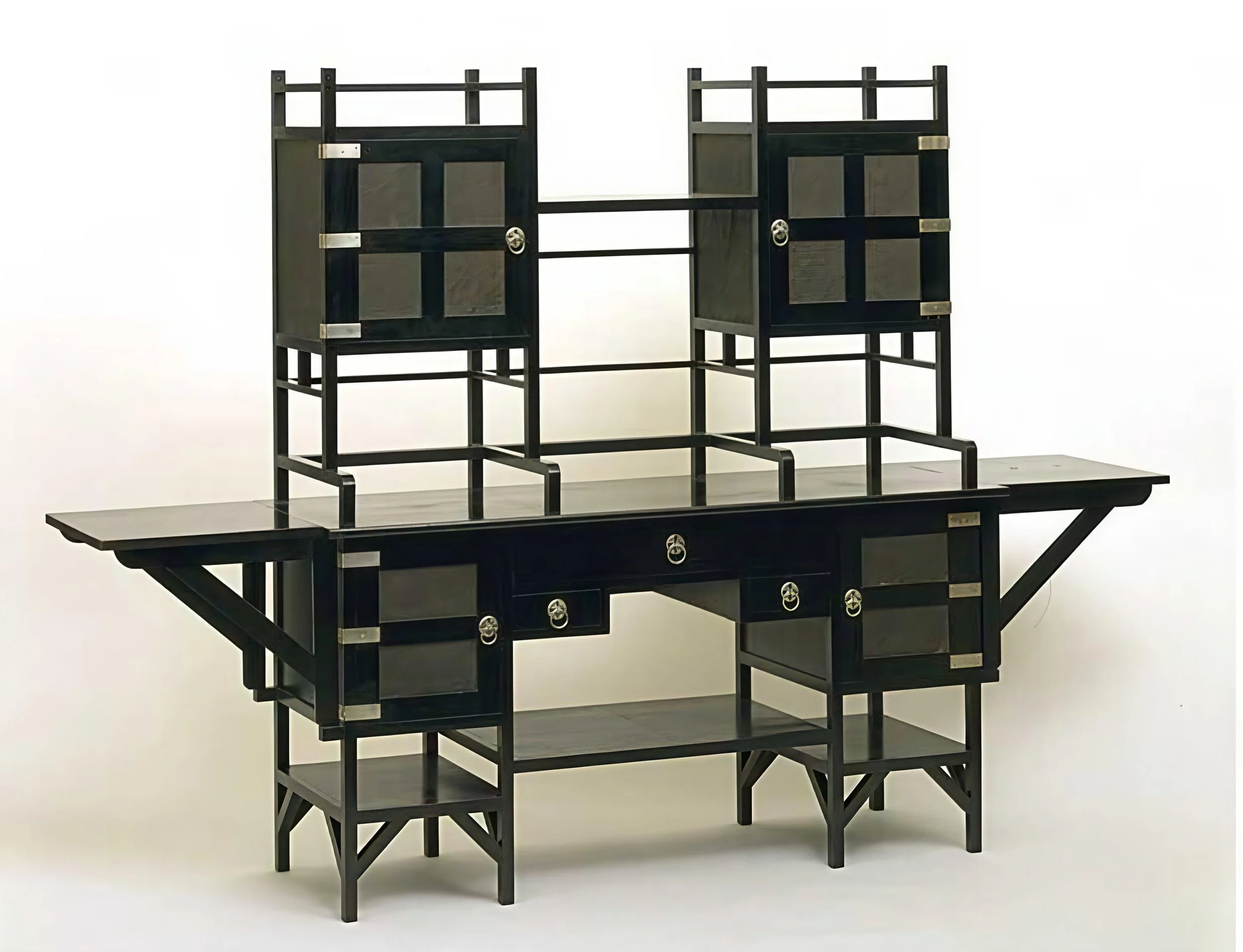 Anglo-Japanese sideboard of ebonized mahogany, embossed sliver panels, and silver hardware; the bottom of open shelves, closed storage, and side leaves; below two upper boxes, supported by a composition of slender horizontal and vertical struts