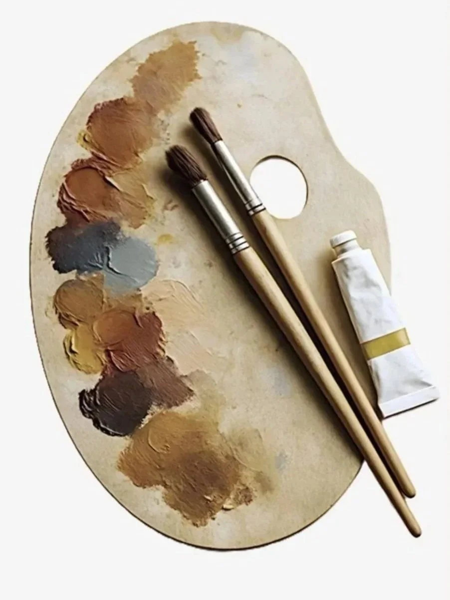 A paint palette with smudges of paint, brushes, and tube of paint
