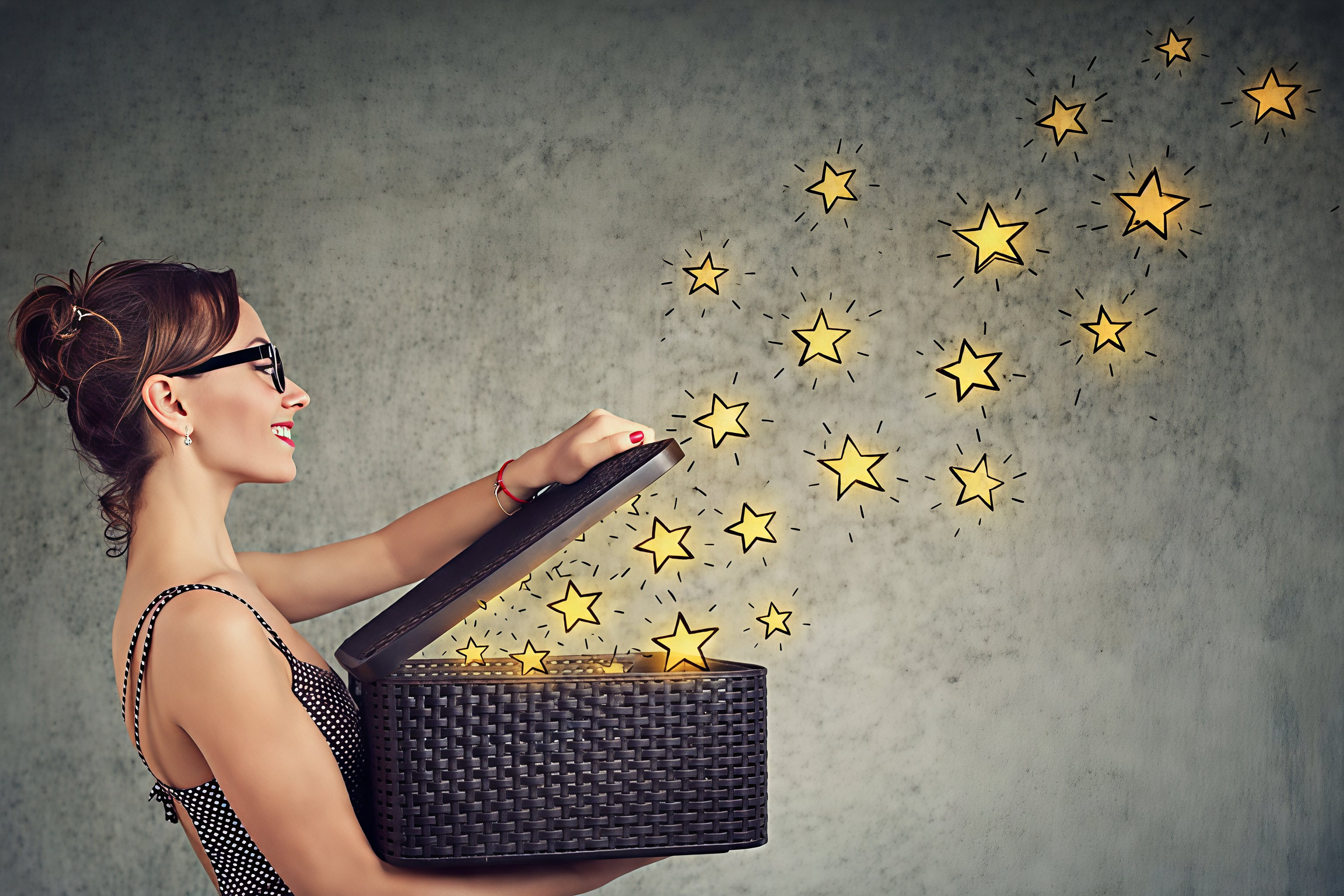 Young woman holding open the lid of a basket from which stars, representing ideas, emerge and disperse