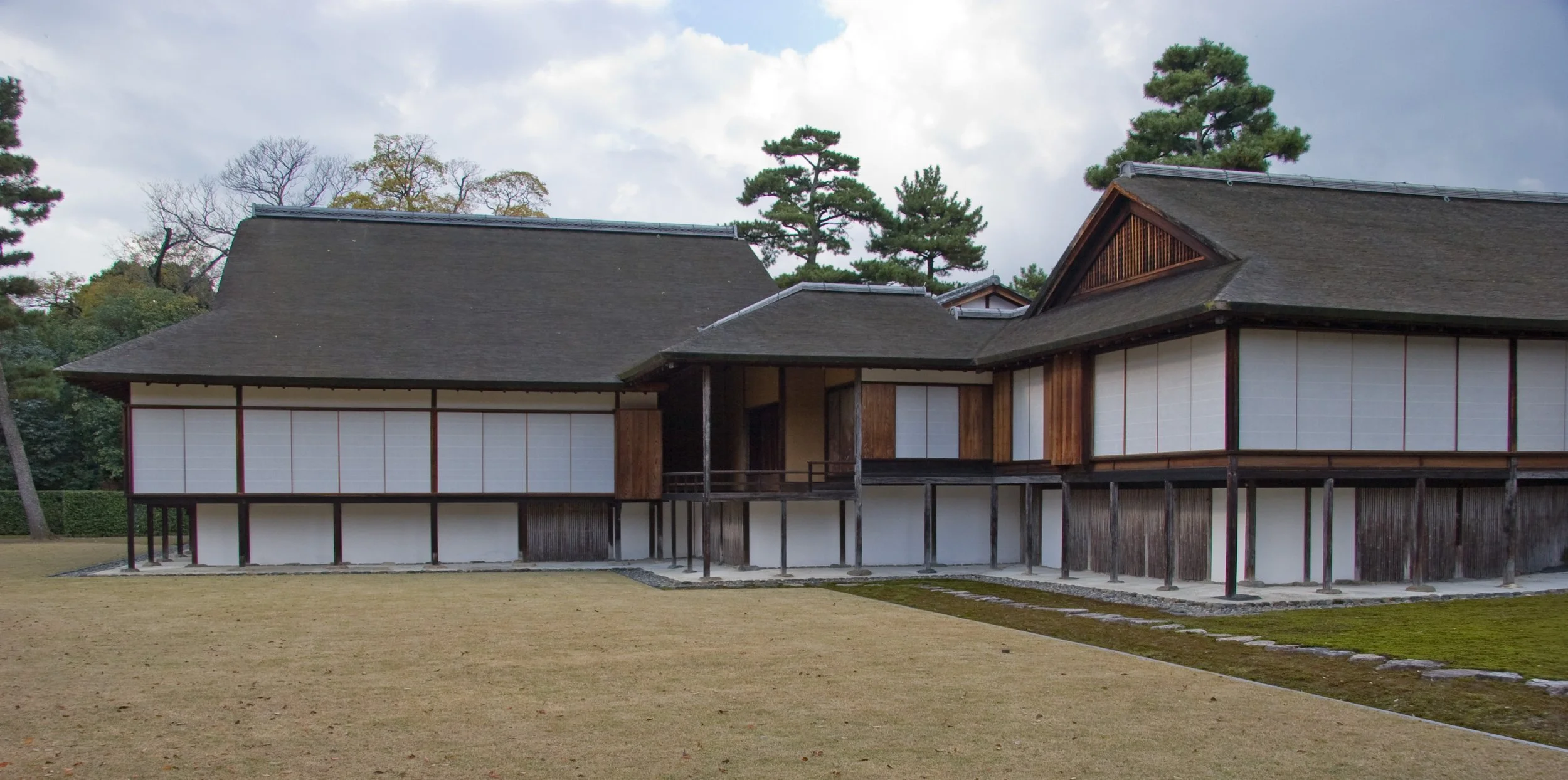 A Japanese villa, consisting of an organic plan and white walls with slender vertical elements defining the bays and slightly heavier verticals supporting the main structure