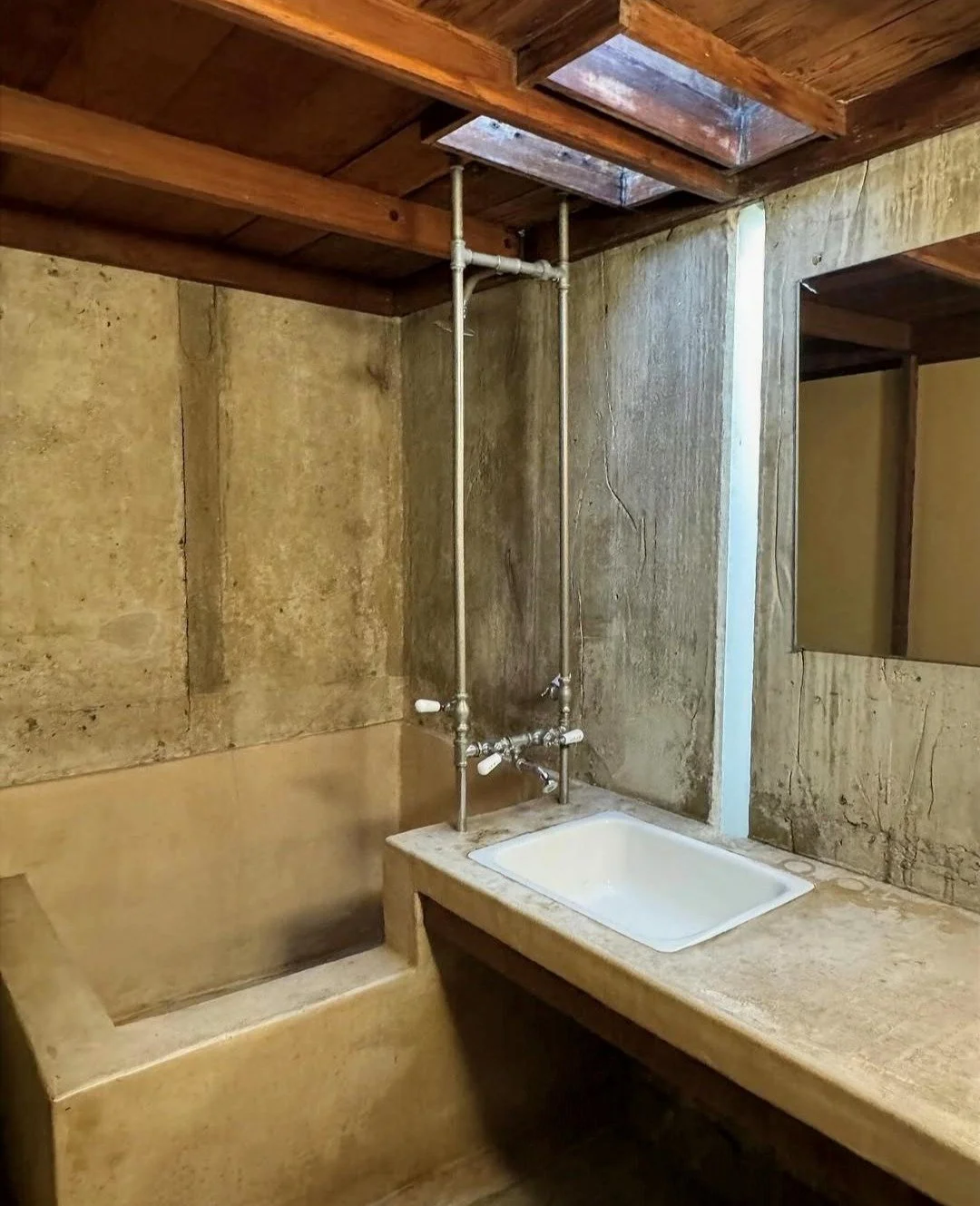 Bathroom in Rudolf Schindler's Kings Road House, where exposed plumbing, raw concrete, and exposed timber beams demonstrate Schindler's commitment to material authenticity, structural honesty, and early Modernist simplicity.
