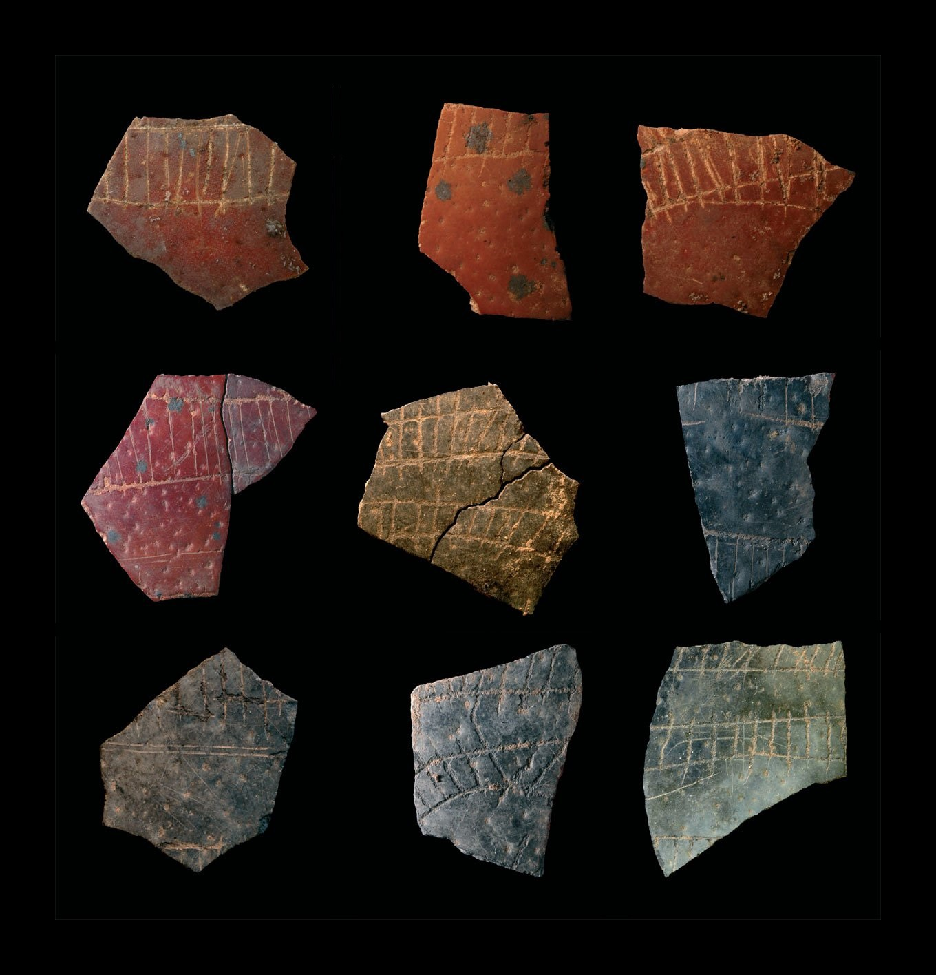 9 pieces of multi-colored, broken, ostrich eggshells with incised patterns resembling small railroad tracks.  c.60,000 BCE. From Diepkloof, South Africa.