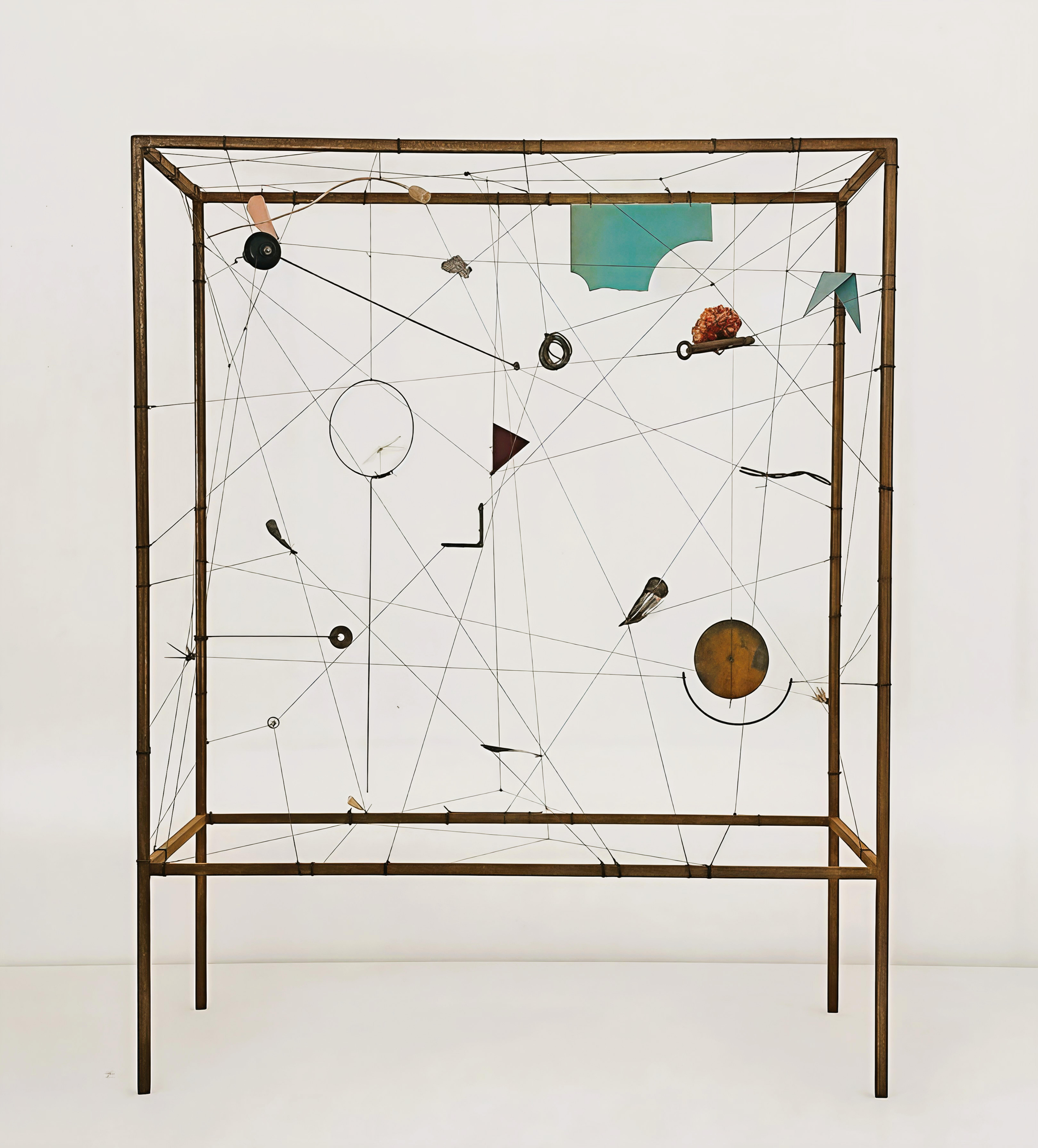 a work of sculpture that is an open metal box on a metal stand with various objects suspended within it and connected to each other by wires in no particular pattern