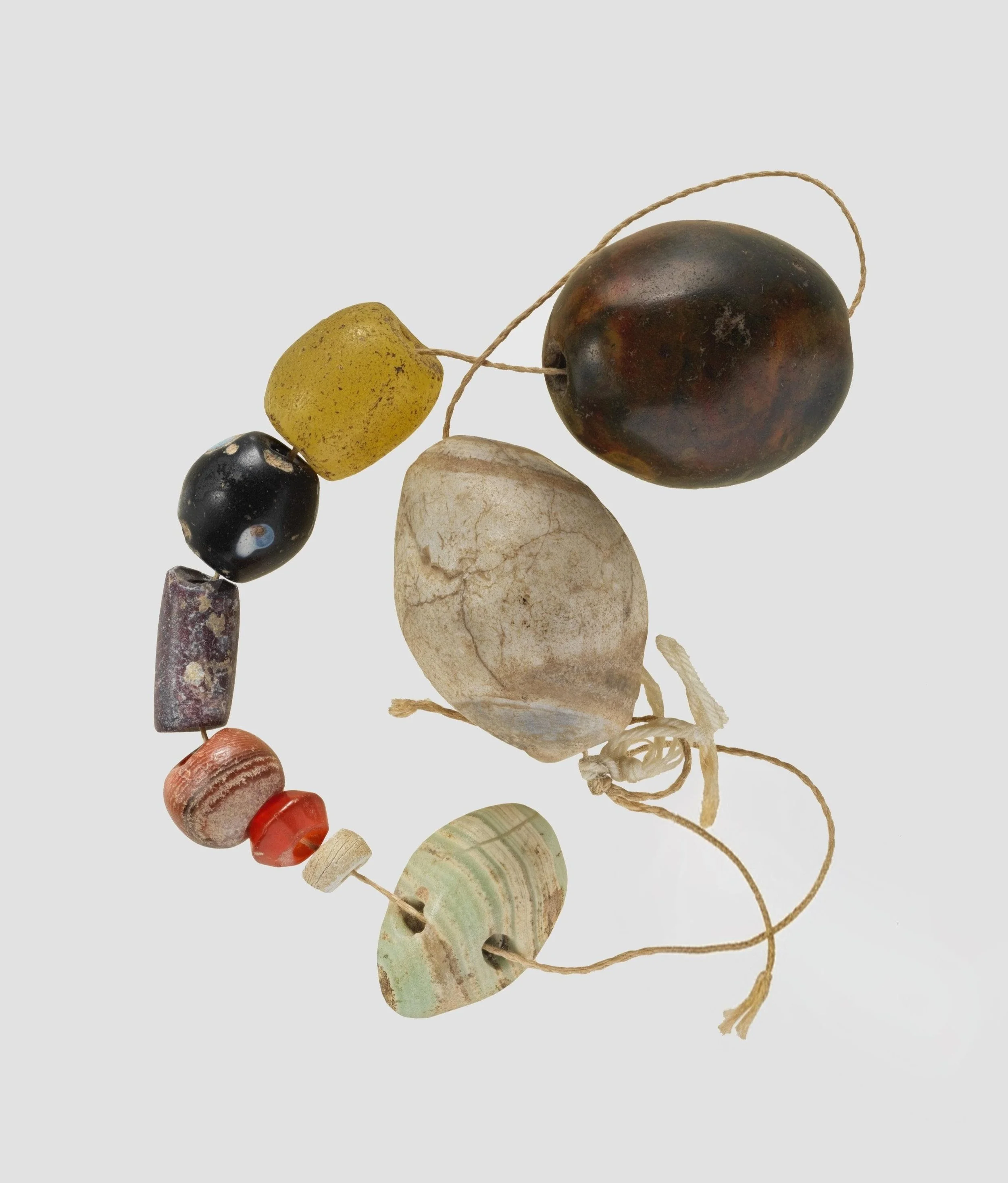 Prehistoric stone beads of varied shapes and materials arranged together