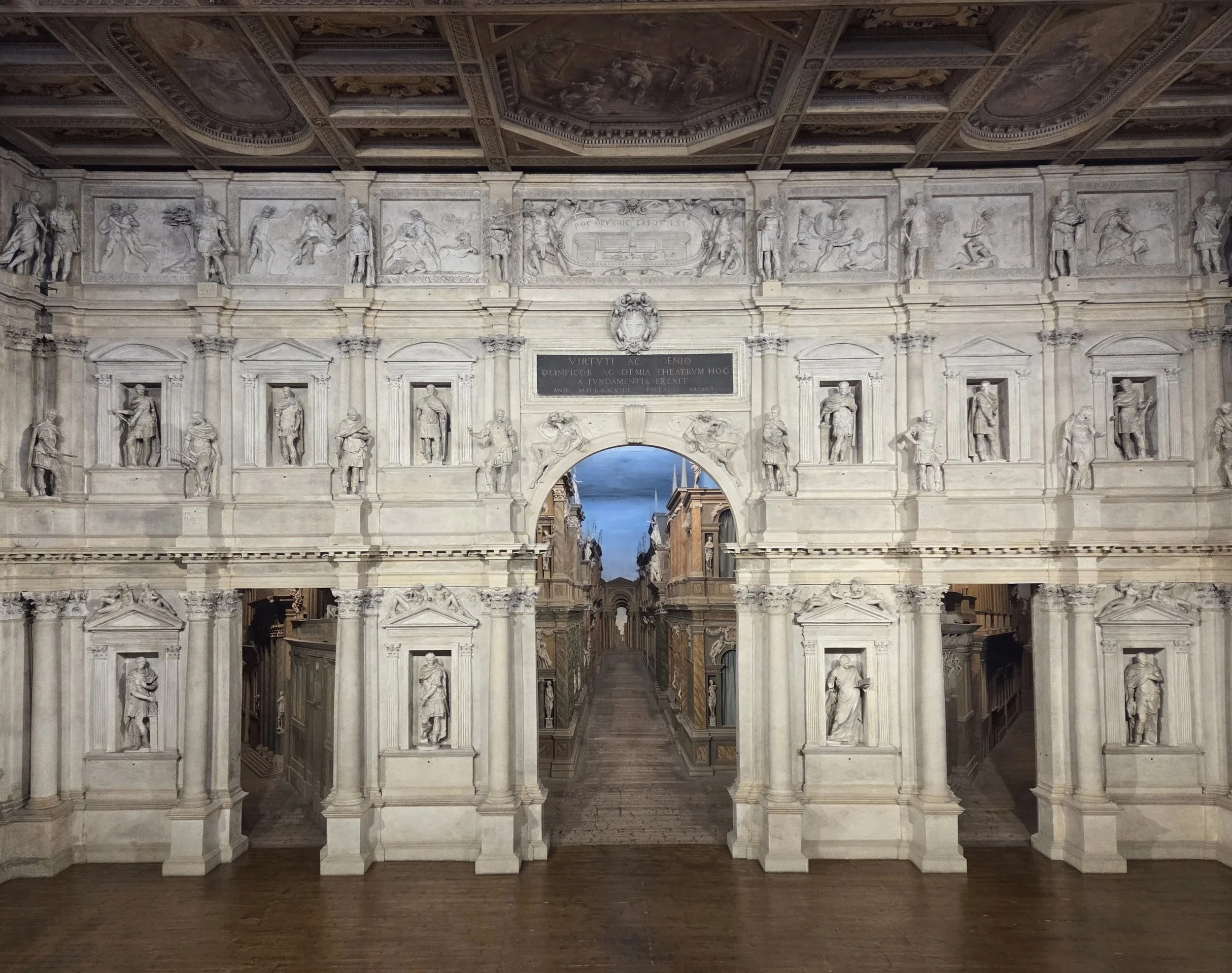 A proscenium with an extensive backdrop of  Roman-style Classical facade with a central arch opening onto a dramatic one-point perspective