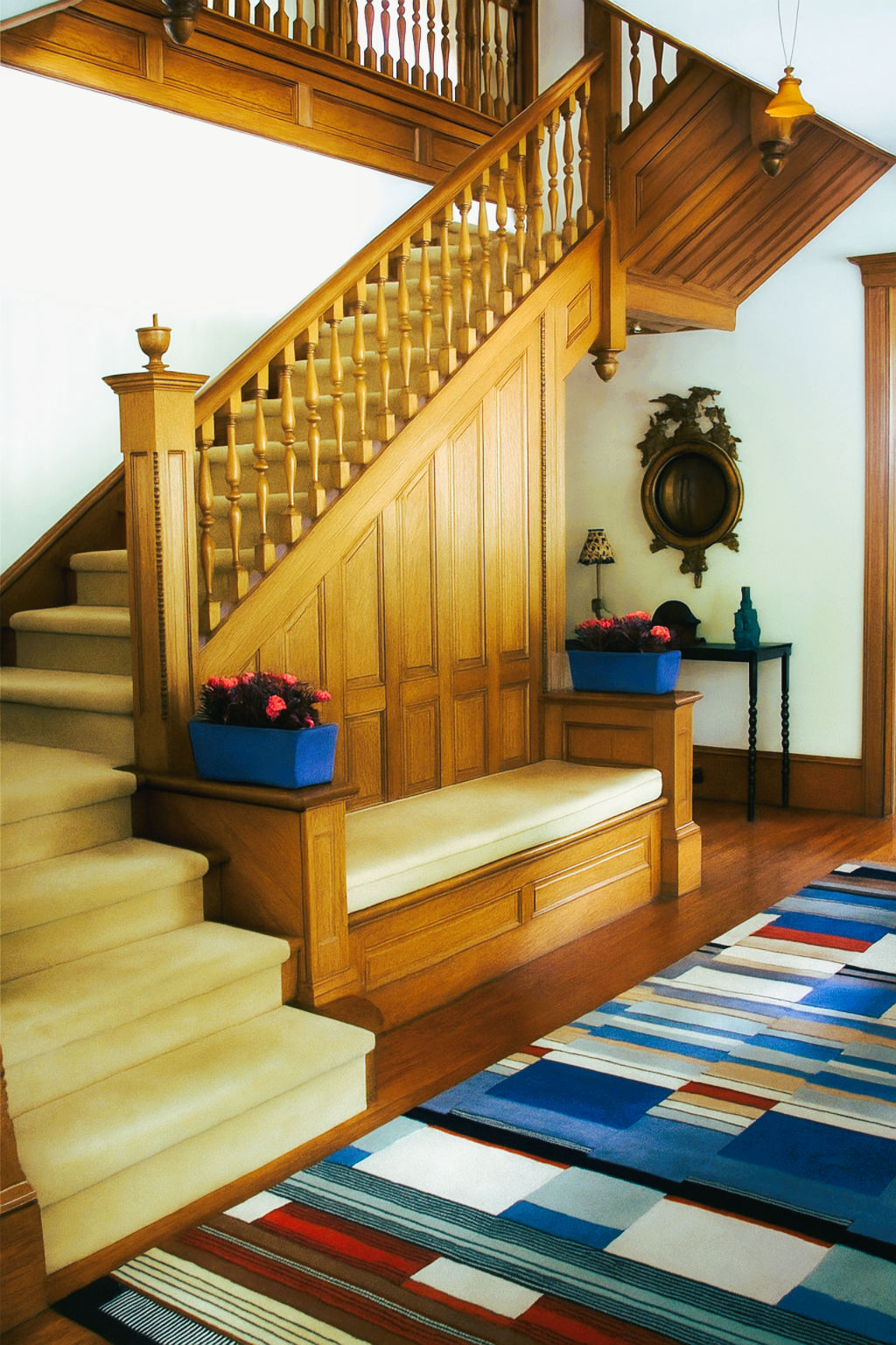 an entry hall of an early 20th century house with traditional millwork staircase and paneling and a very modern colorful carpet