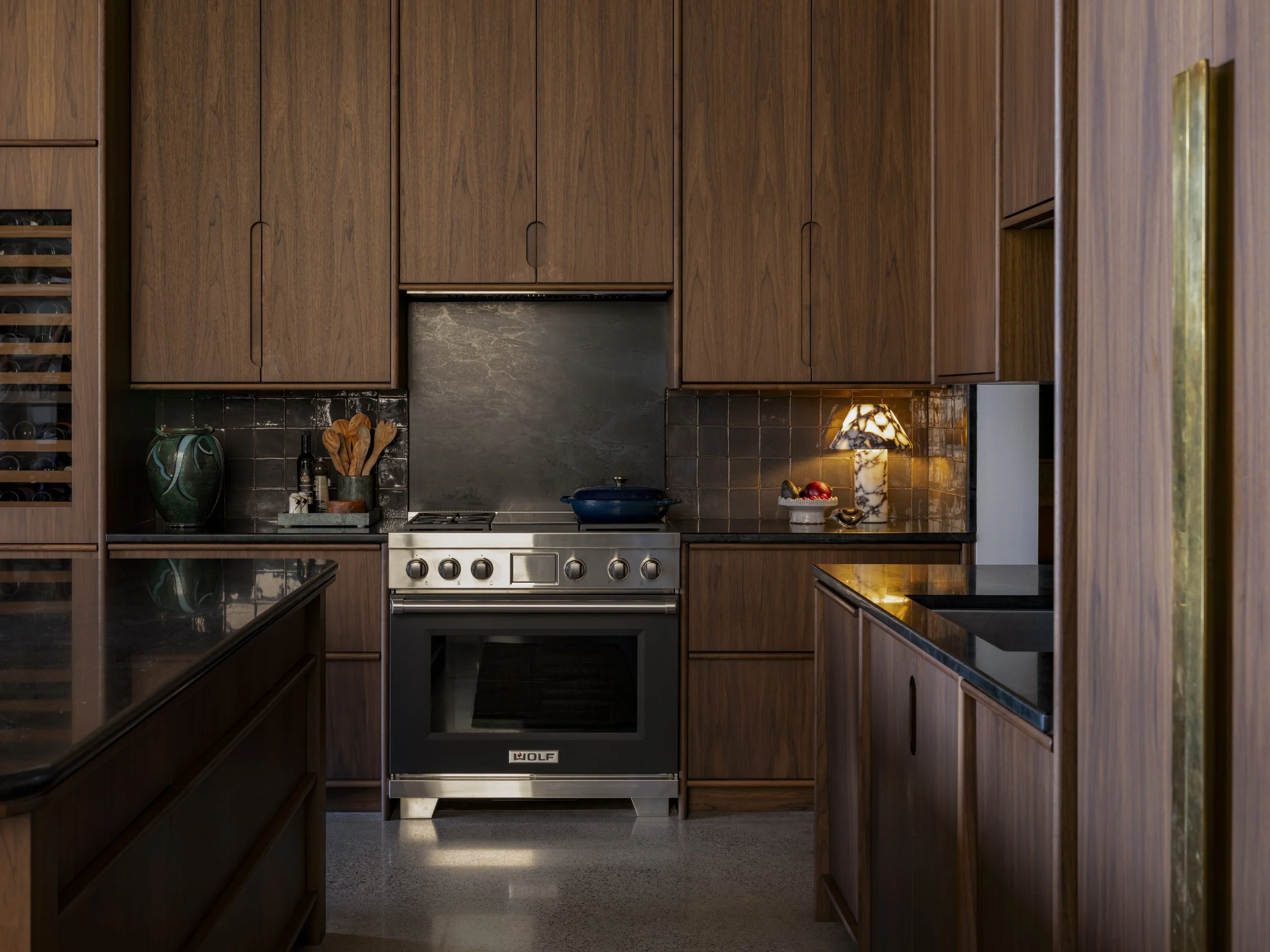 A kitchen with wooden cabinets, a stove, a lamp, and various kitchen items.