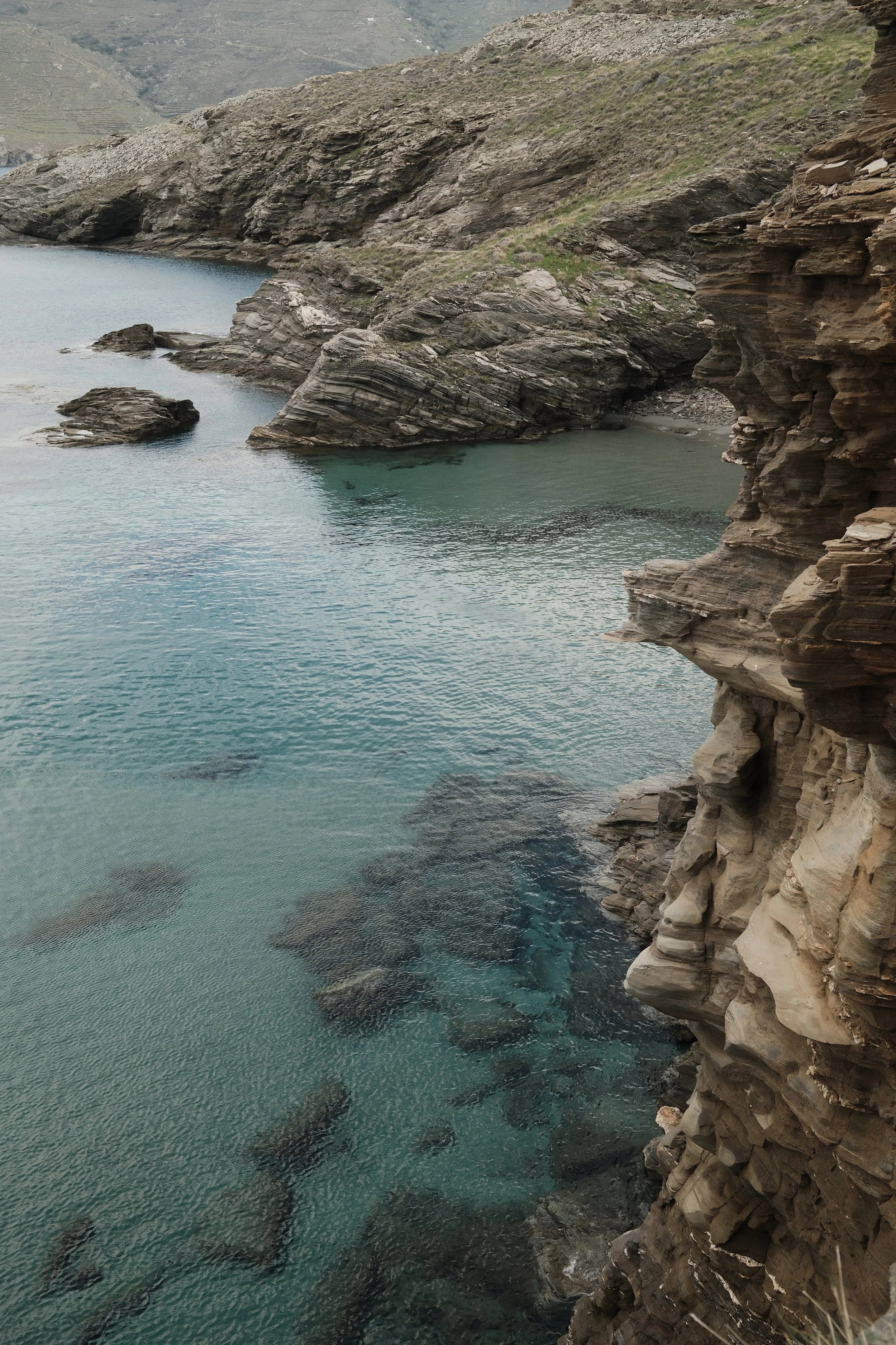 Bjerge og klippeformationer ved en rolig, blågrøn sø.