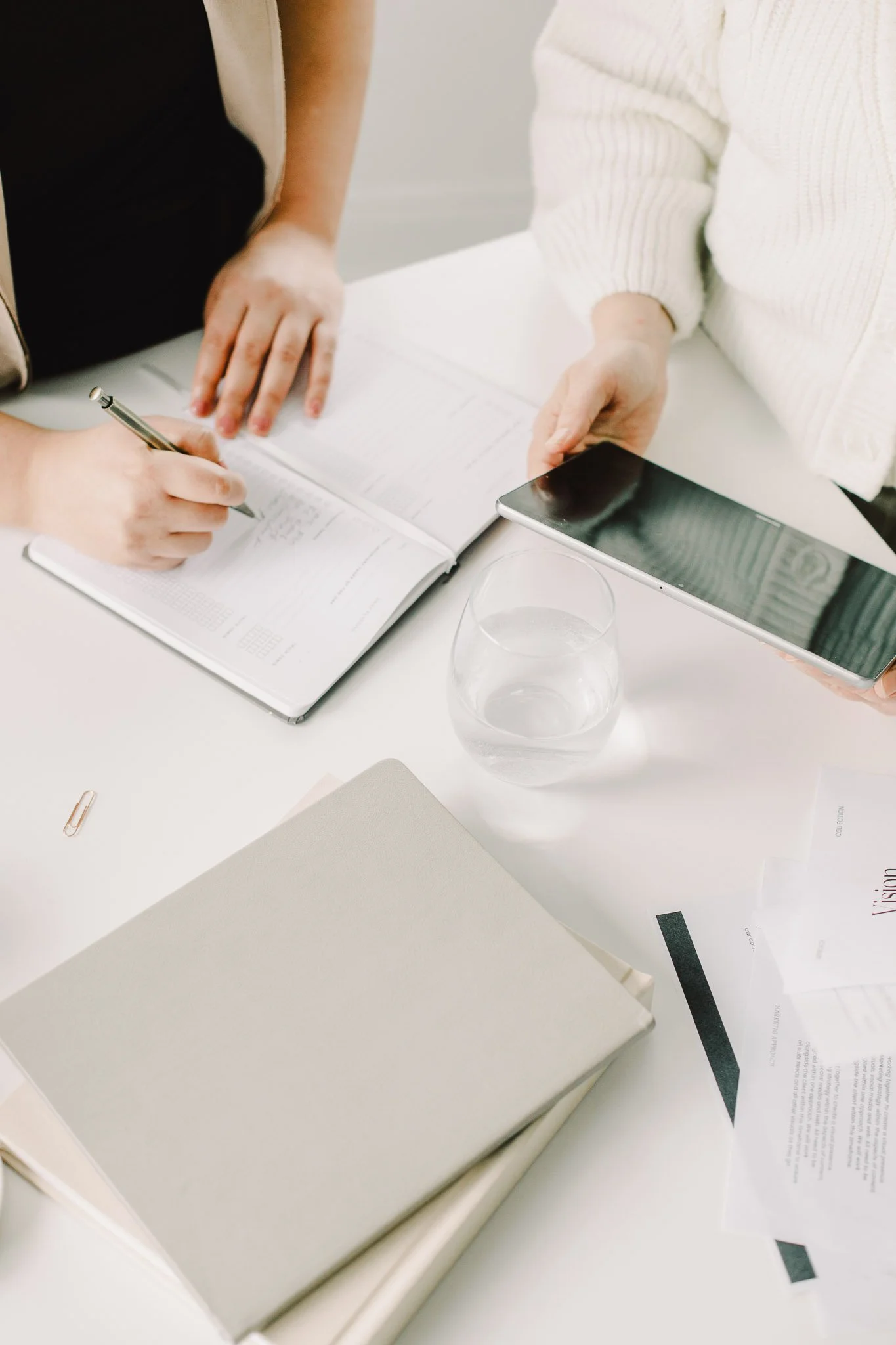 Two business owners reviewing marketing strategy with notebook and tablet during a planning session.