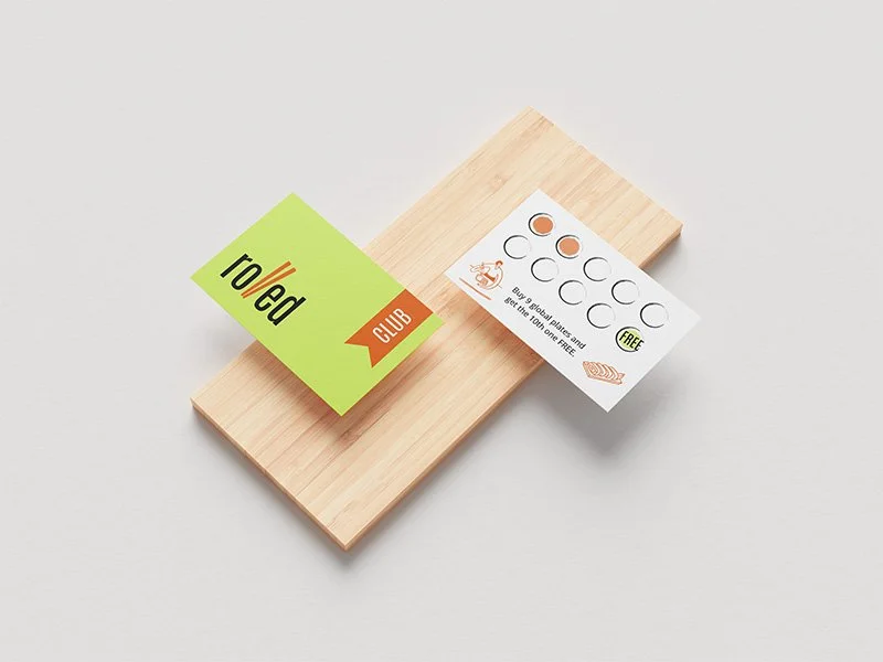 Minimal business card design for a sushi restaurant, displayed on a wooden block.