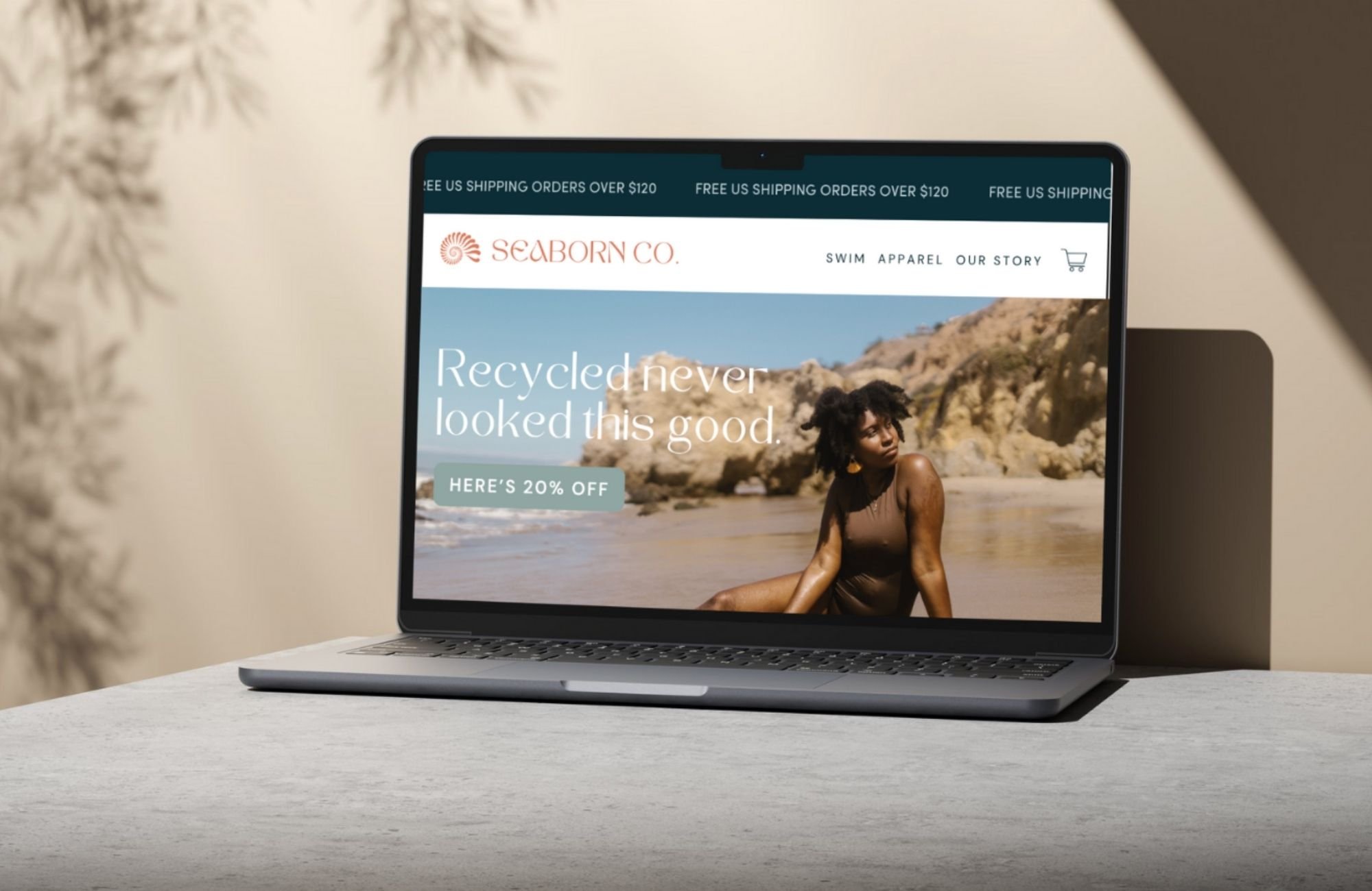 Laptop mockup displaying an ethical swimwear e-commerce website homepage design with coastal photography and sustainable fashion messaging.