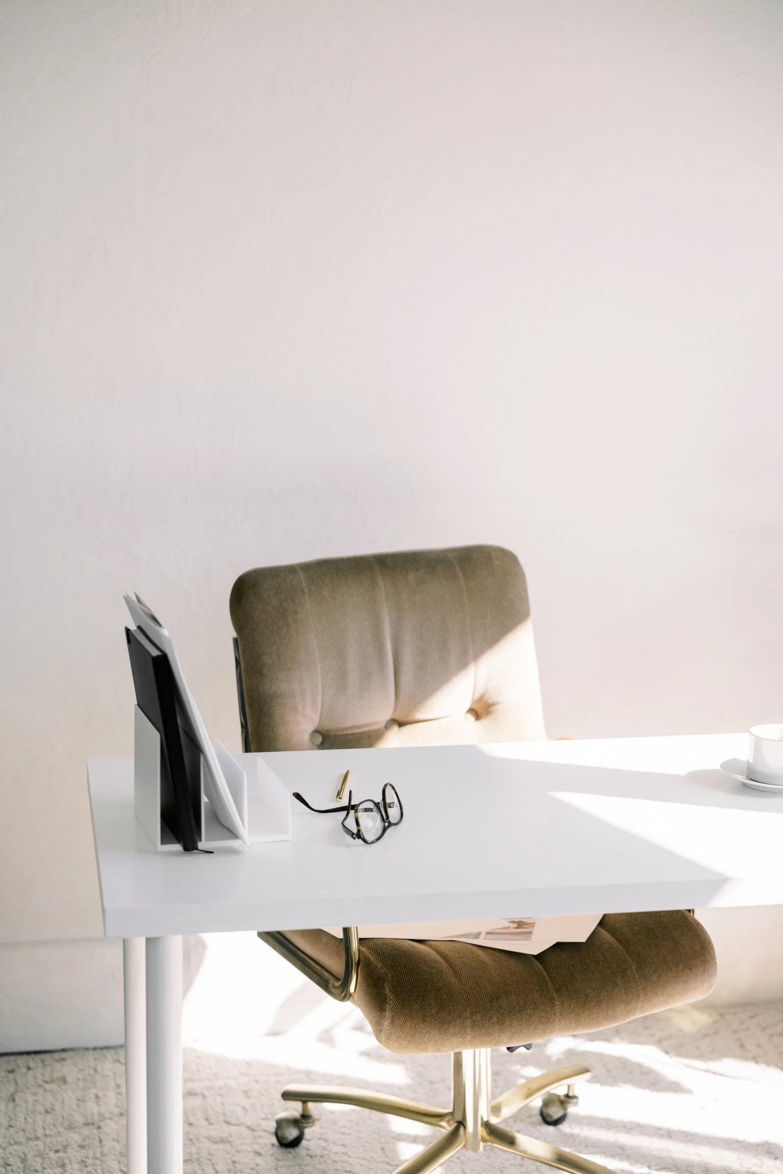 A clean, minimal desk setup in California with glasses and a comfortable chair, showing the professional creative workspace behind Aviso Studios a marketing agency.