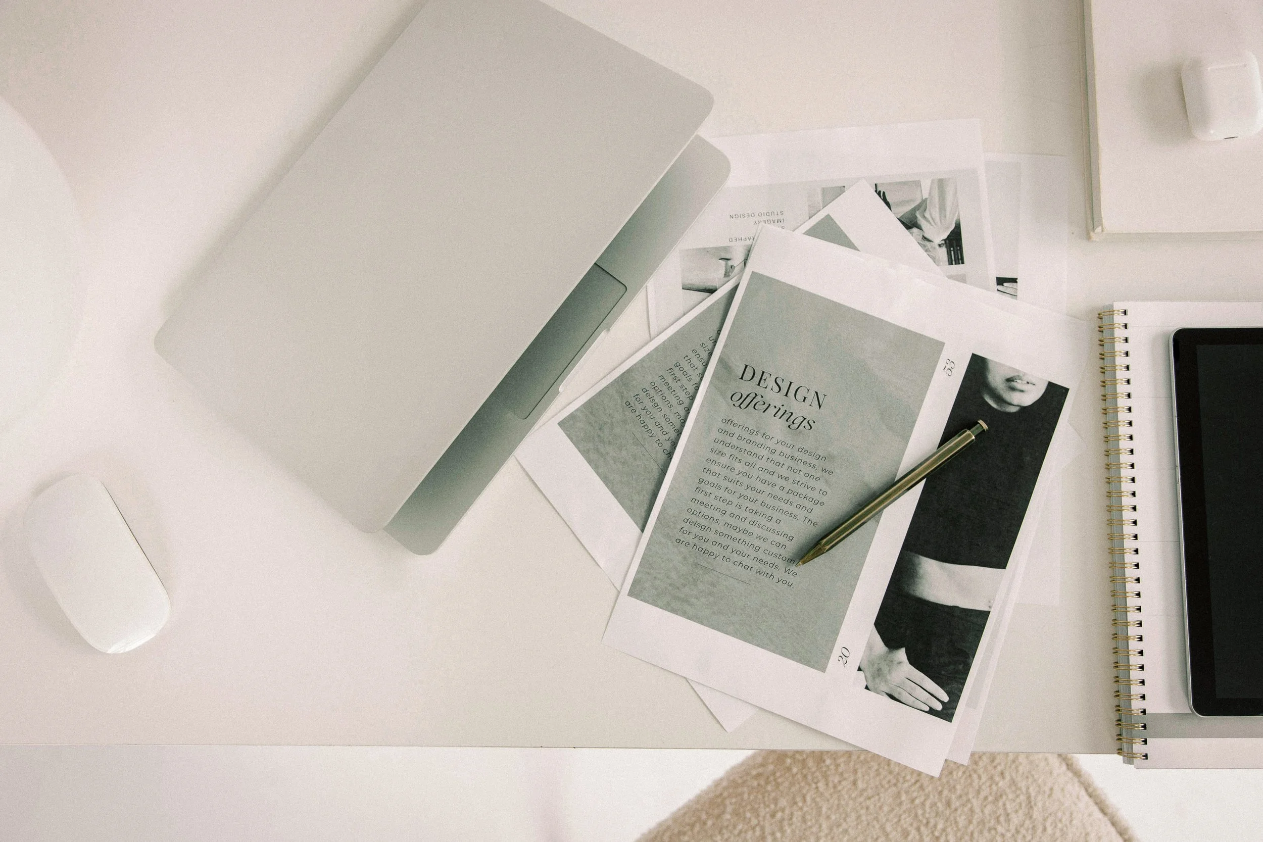 A flatlay with a laptop, design mockups, and notes on a desk — representing the strategic branding and website design process.