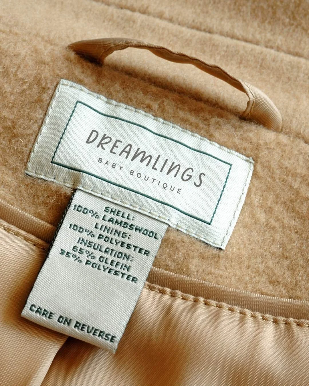Close-up of a Dreamlings clothing label on a soft tan fabric, highlighting materials and care instructions with a minimalist, elegant design.