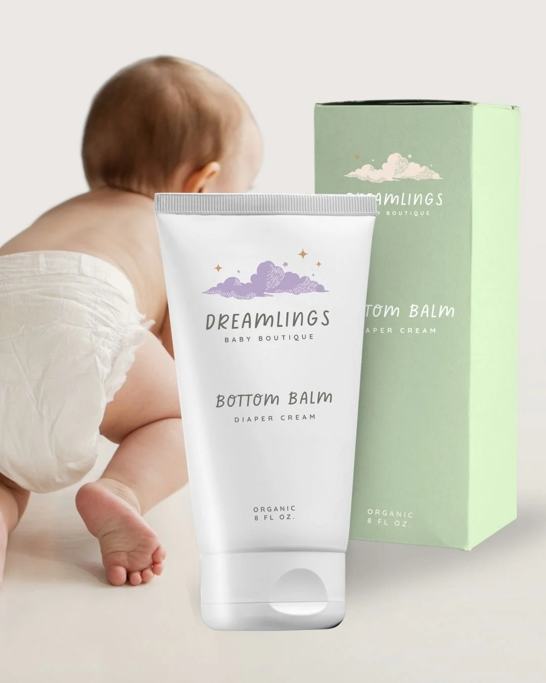 Dreamlings’ Bottom Balm diaper cream in whimsical packaging, featuring pastel green tones and a crawling baby in the background.