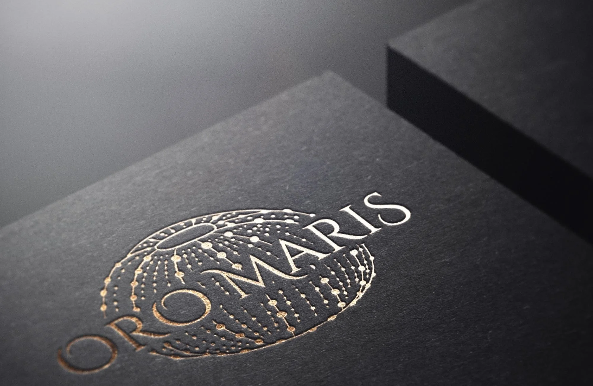 Close-up of custom logo for luxury seafood restaurant featuring embossed gold foil sea urchin design on dark textured paper.