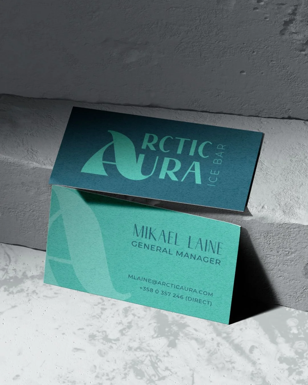 Business card for Mikael Laine, General Manager, at Arctic Aura Ice Bar, placed against a textured white wall and casting a shadow on a textured white surface.
