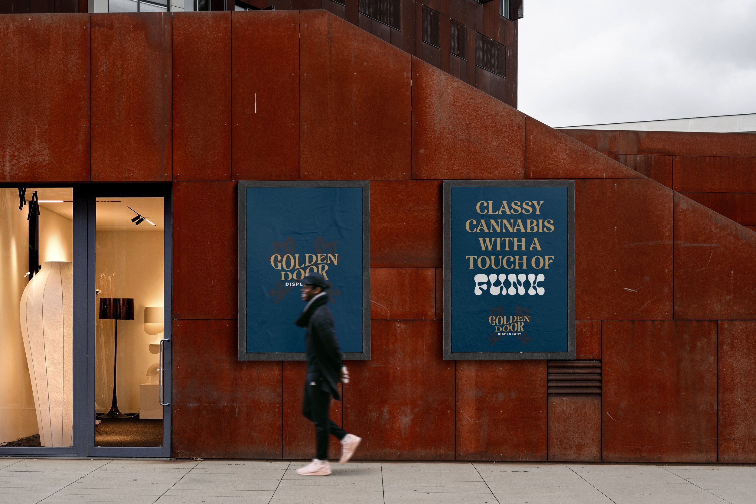 A person walking past two large blue signs on a rust-colored building wall. The left sign reads 'GOLDEN DOOR DISPENSARY,' and the right sign says 'CLASSY CANNABIS WITH A TOUCH OF FUNK.' A glass door with interior lights and lamps is visible to the le