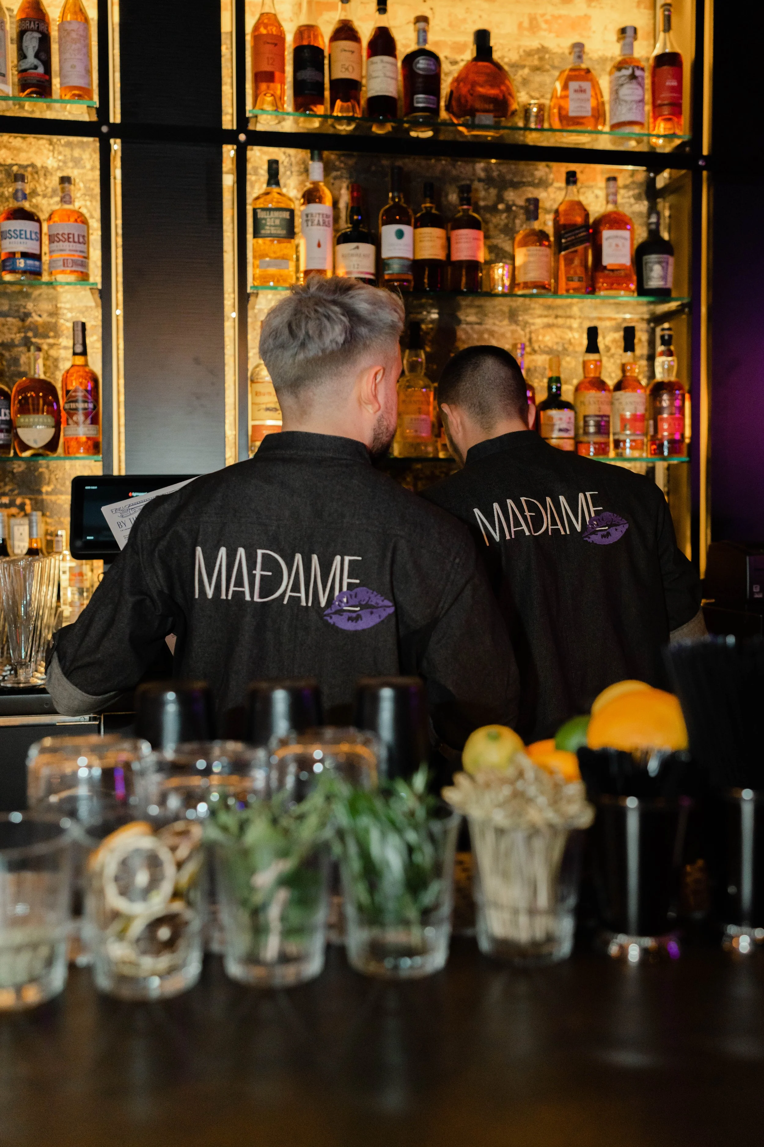 Two bartenders wearing black shirts with 