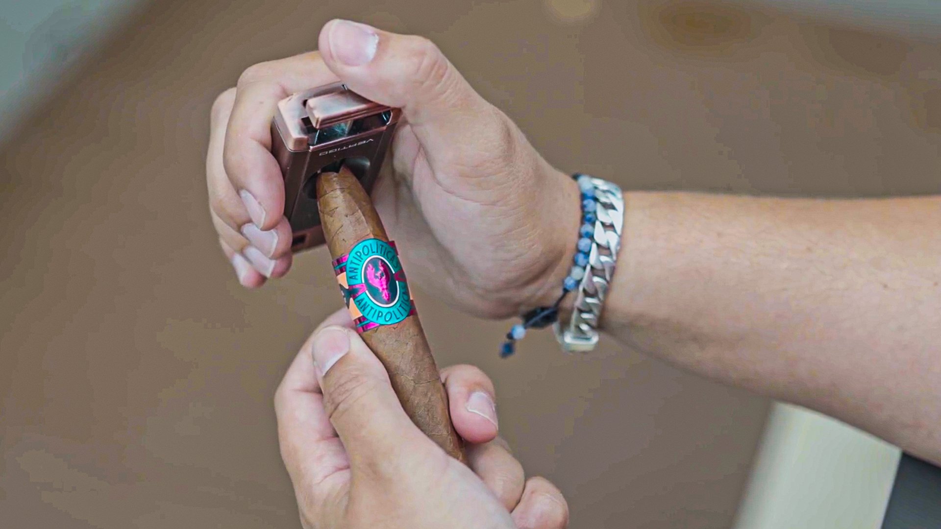 A hand holding a cigar with an anti-police sticker while using a lighter to ignite the cigar.