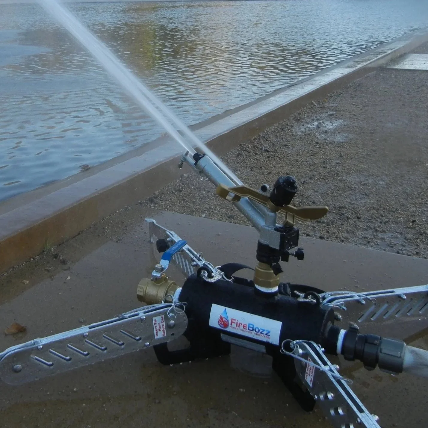 Water spraying from a fire suppression device near a body of water on a concrete surface.