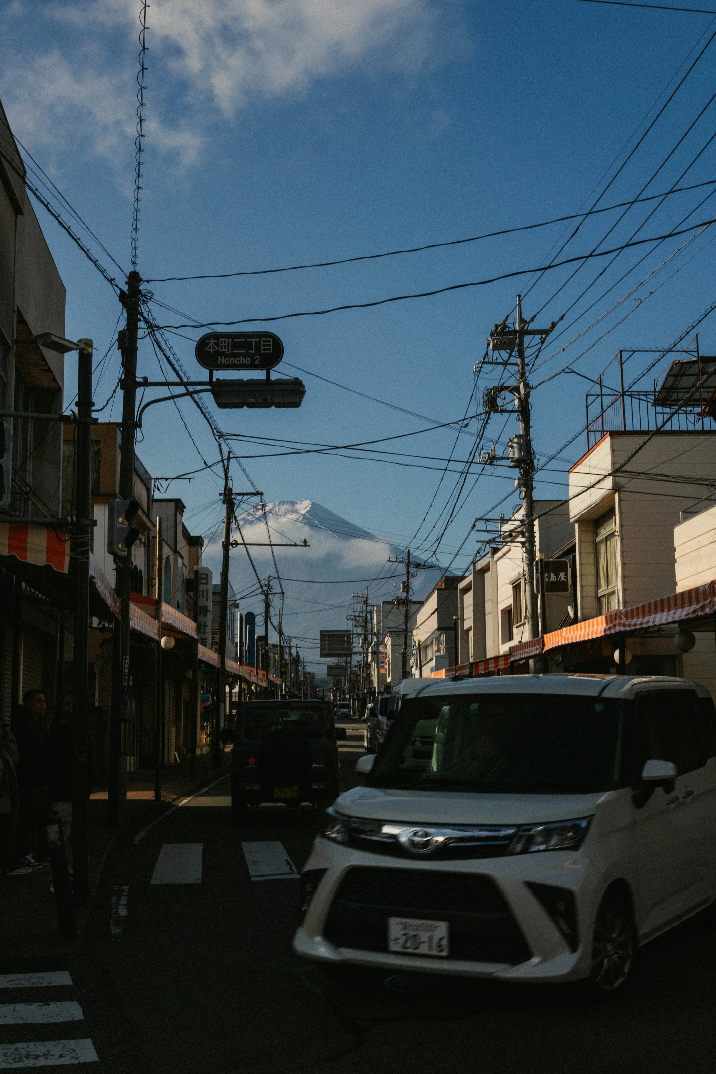 Fotografía editorial de viaje en Japón. Monte Fuji al fondo y calle comercial en primer plano, combinando vida cotidiana, paisaje y contexto urbano.