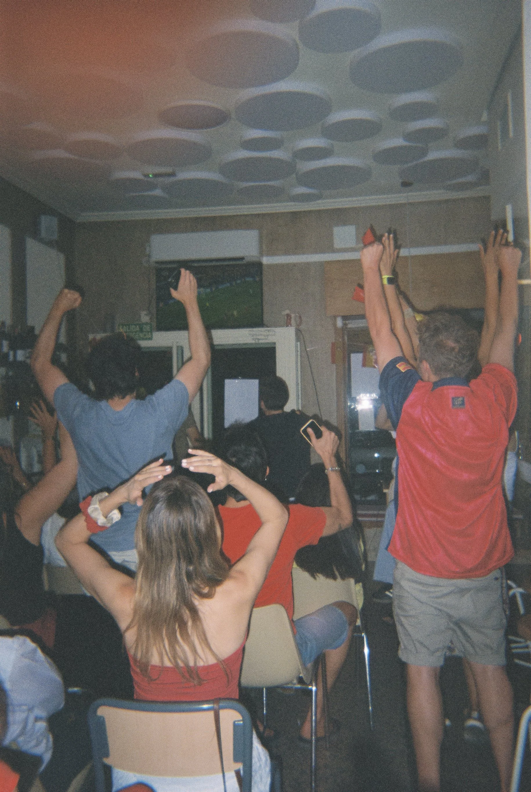 Aficionados celebrando la victoria de España en el Mundial 2026 desde un bar, fotografía analógica
