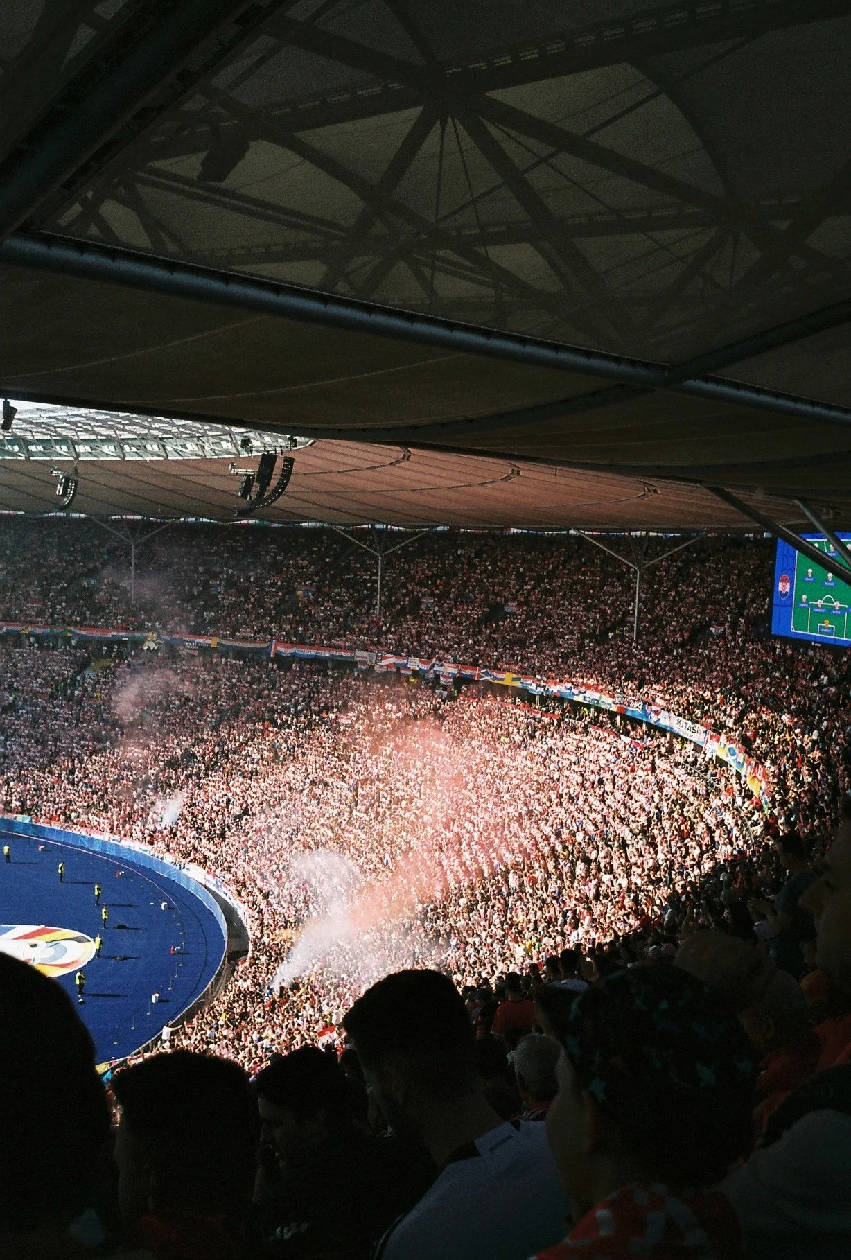Grada del estadio repleta de aficionados con bengalas durante la celebración de la Eurocopa 2024, fotografía analógica