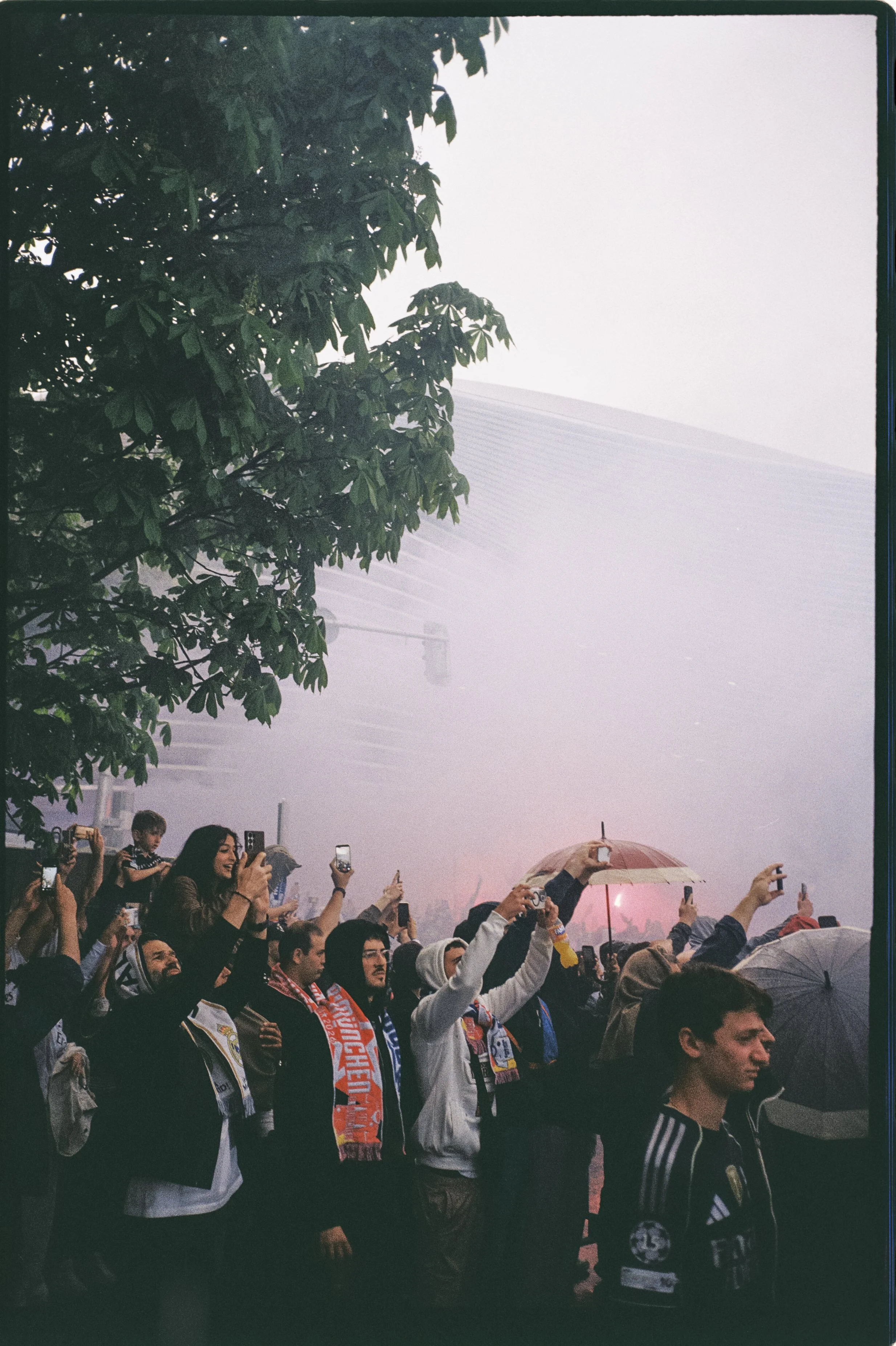 Aficionados con bengala frente al estadio durante una noche de Champions League, fotografía analógica