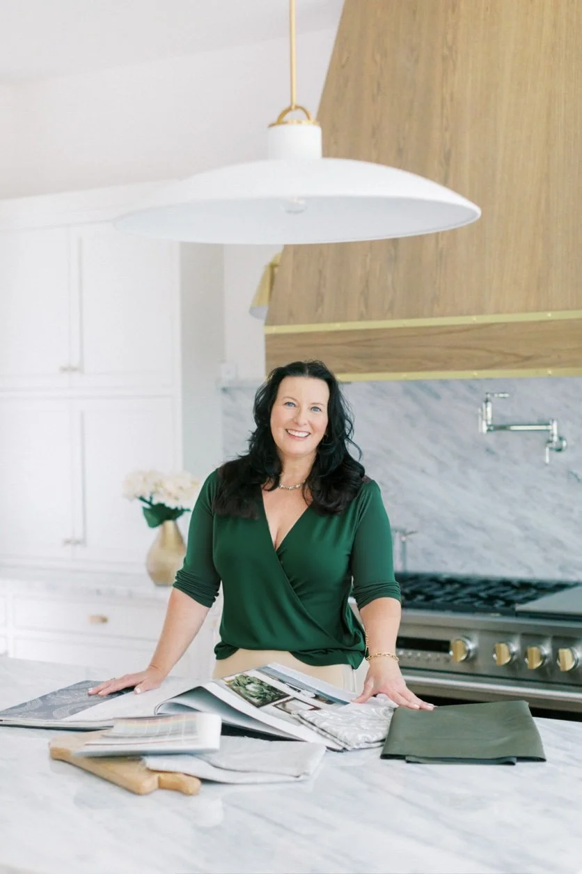 Angela Arnold reviewing design materials in a residential kitchen, combining real estate strategy and interior design to prepare homes for market.