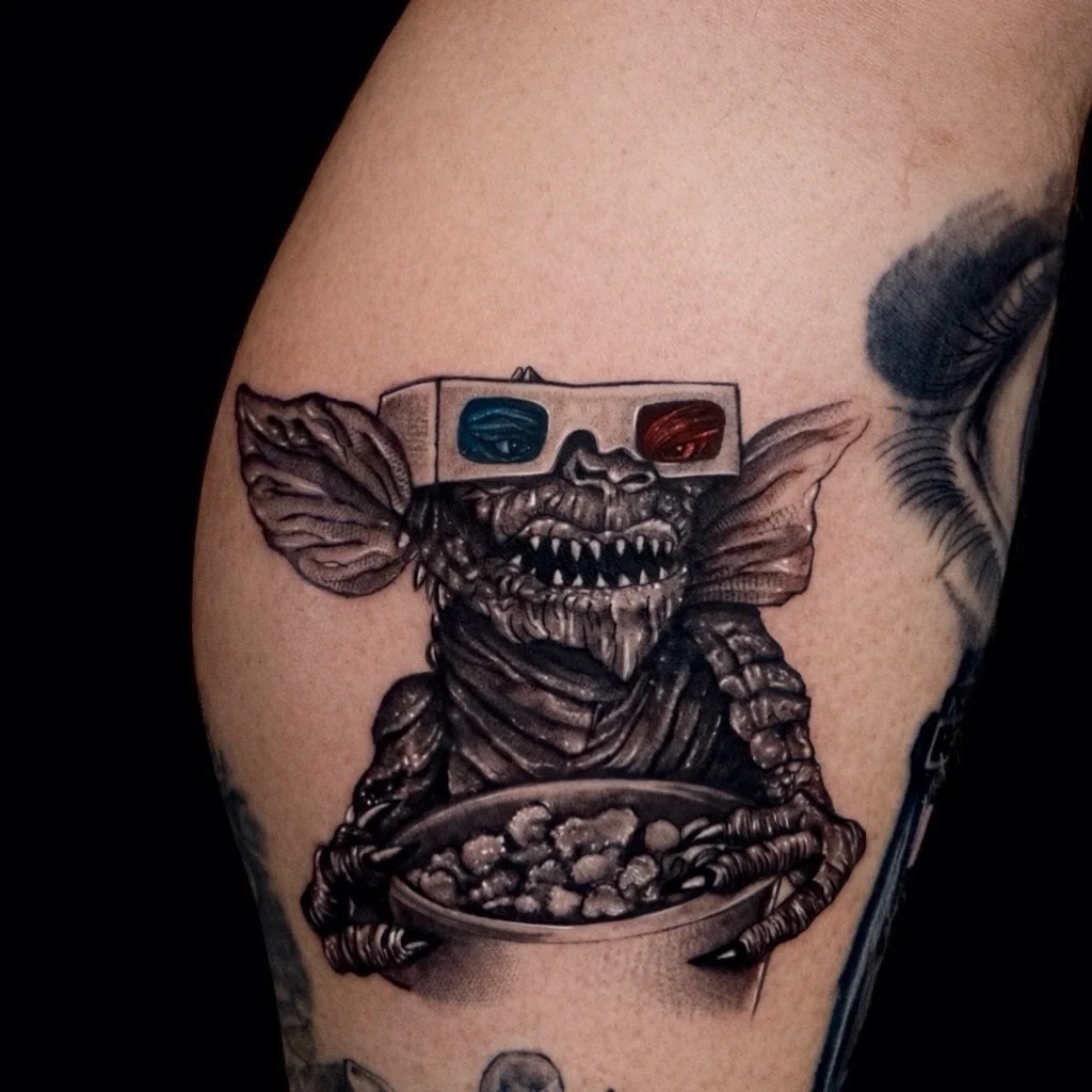 Ein kleiner Chaot mit gro&szlig;em Kino-Vibe.
Dieser freche Gremlin mit 3D-Brille und Popcorn bringt Humor, Nostalgie und eine ordentliche Portion 80s-Feeling unter die Haut.

Detailverliebt gestochen, mit starken Kontrasten und einem Hauch Dunkelhei
