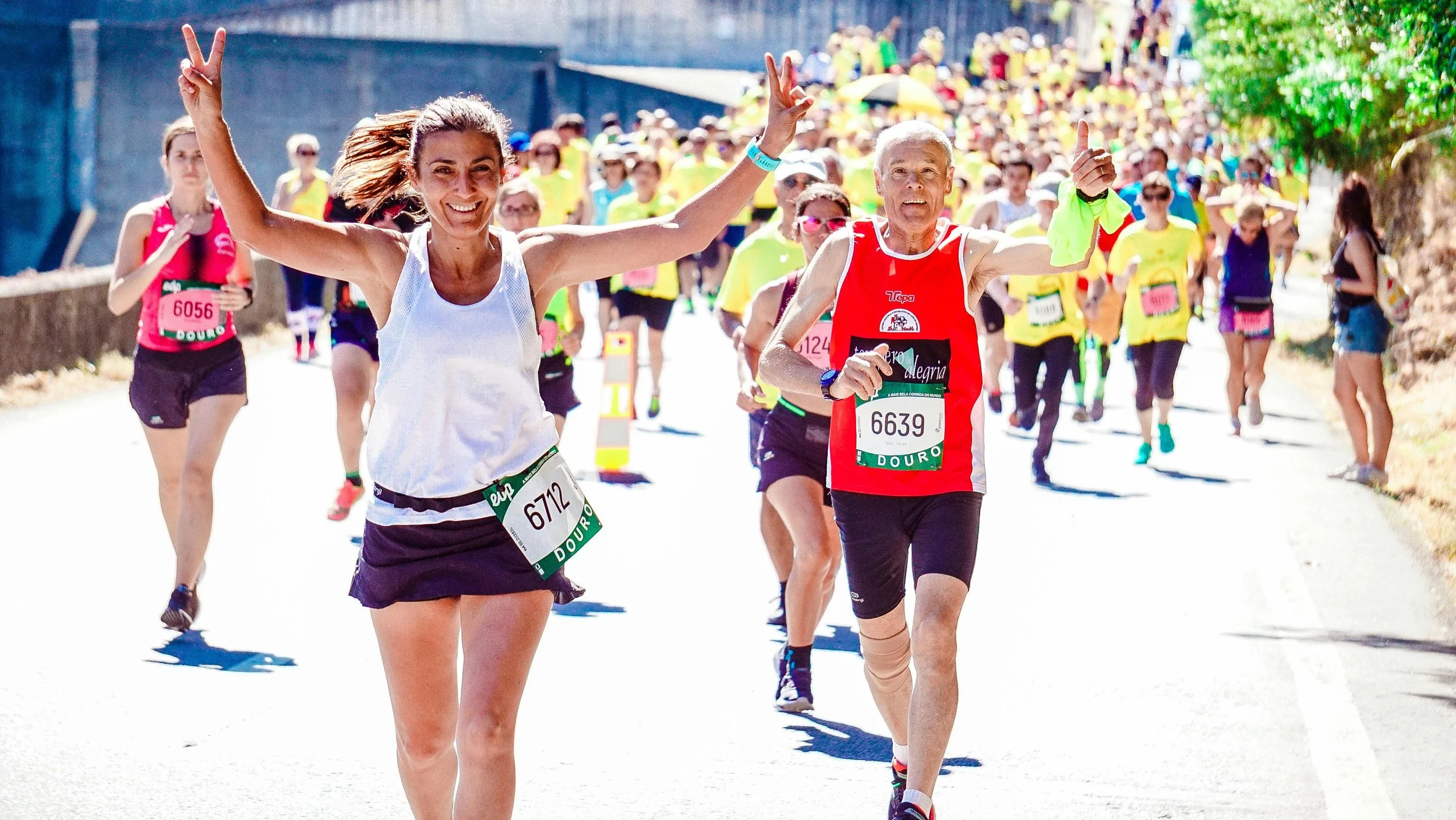 Two runners, a woman and an older man, are running in a race with many participants in the background. exercise for mental health. movement for overall wellness, social connections, caring minds llc