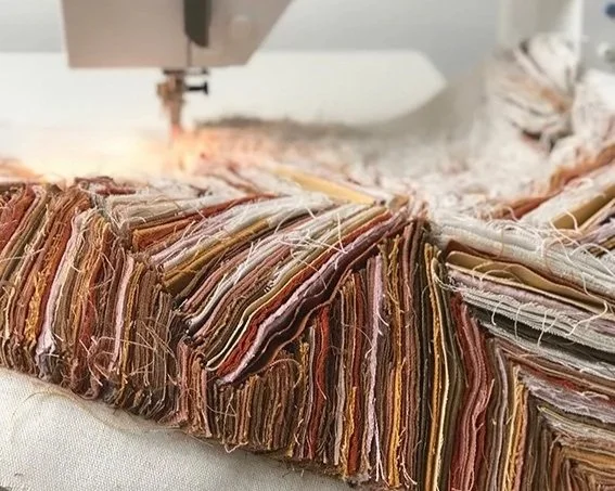 Een lap stof met verschillende kleuren wordt gesneden door een naaimachine.