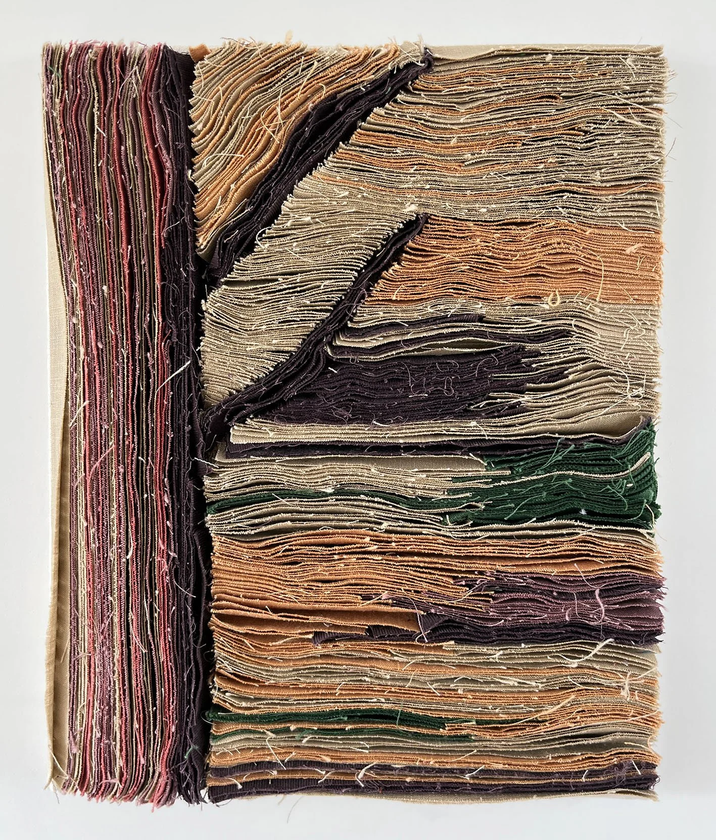 Gestapelde stoffen of tapijten met verschillende kleuren en texturen, op een witte achtergrond.