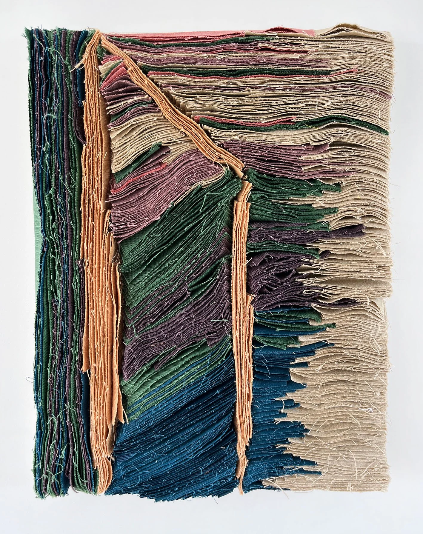 Een close-up van een stapel gevouwen stoffen papier, met verschillende kleuren en texturen.