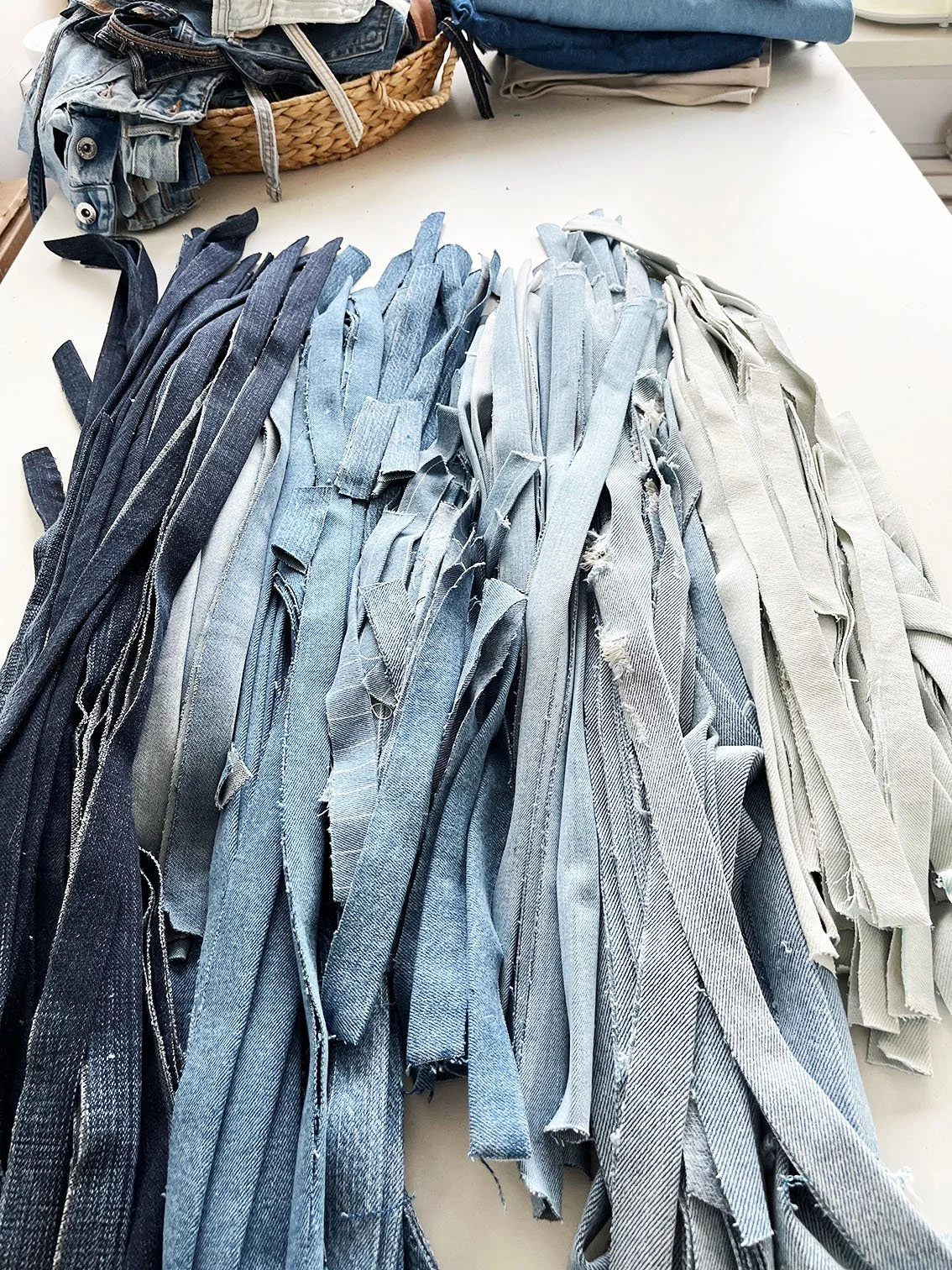 Verzamelingen van jeansbanden in verschillende tinten blauw en wit, uitgespreid op een tafel.