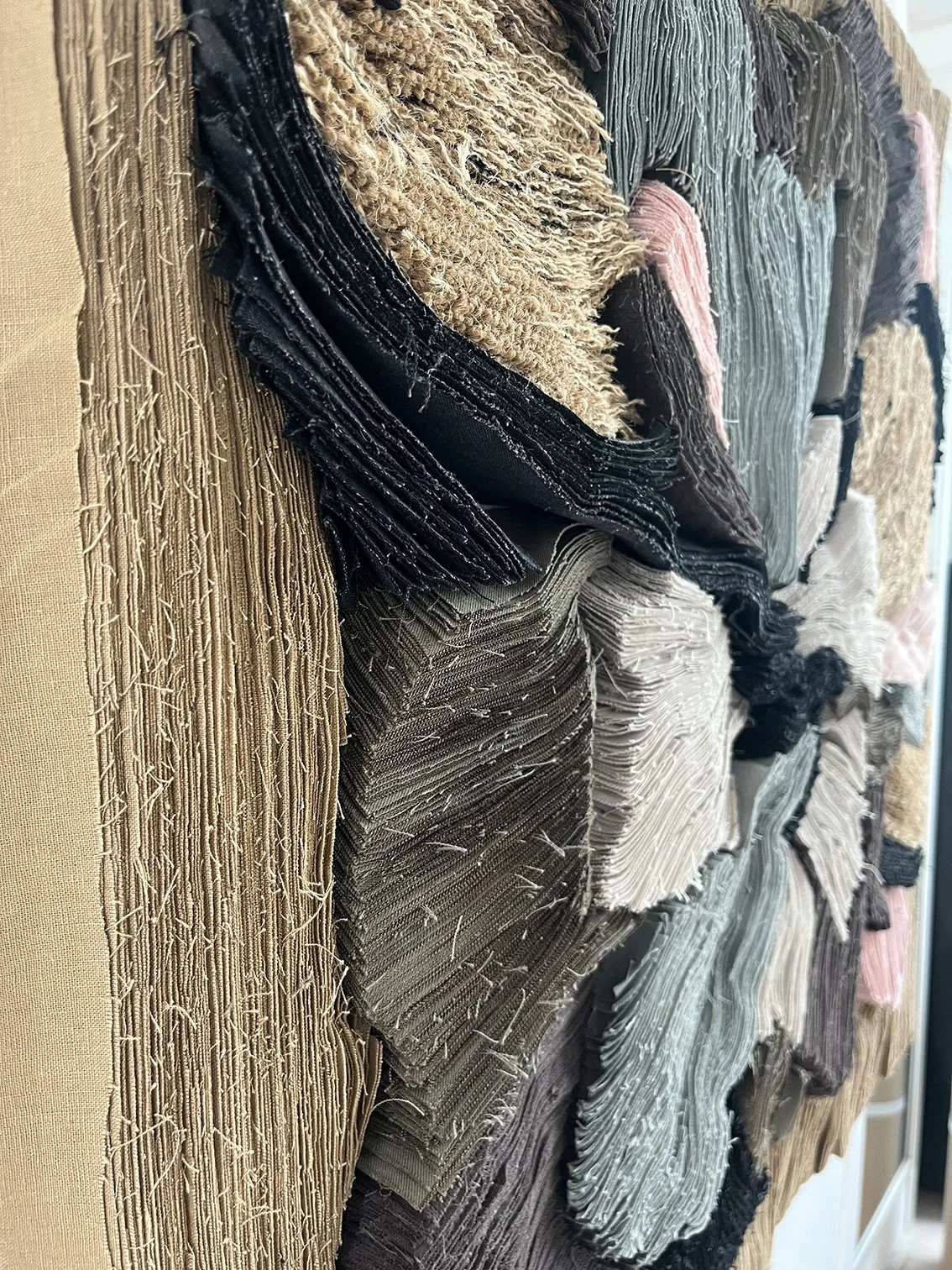 Diverse stukjes stof of tapijt in verschillende kleuren en texturen, opgestapeld samen.