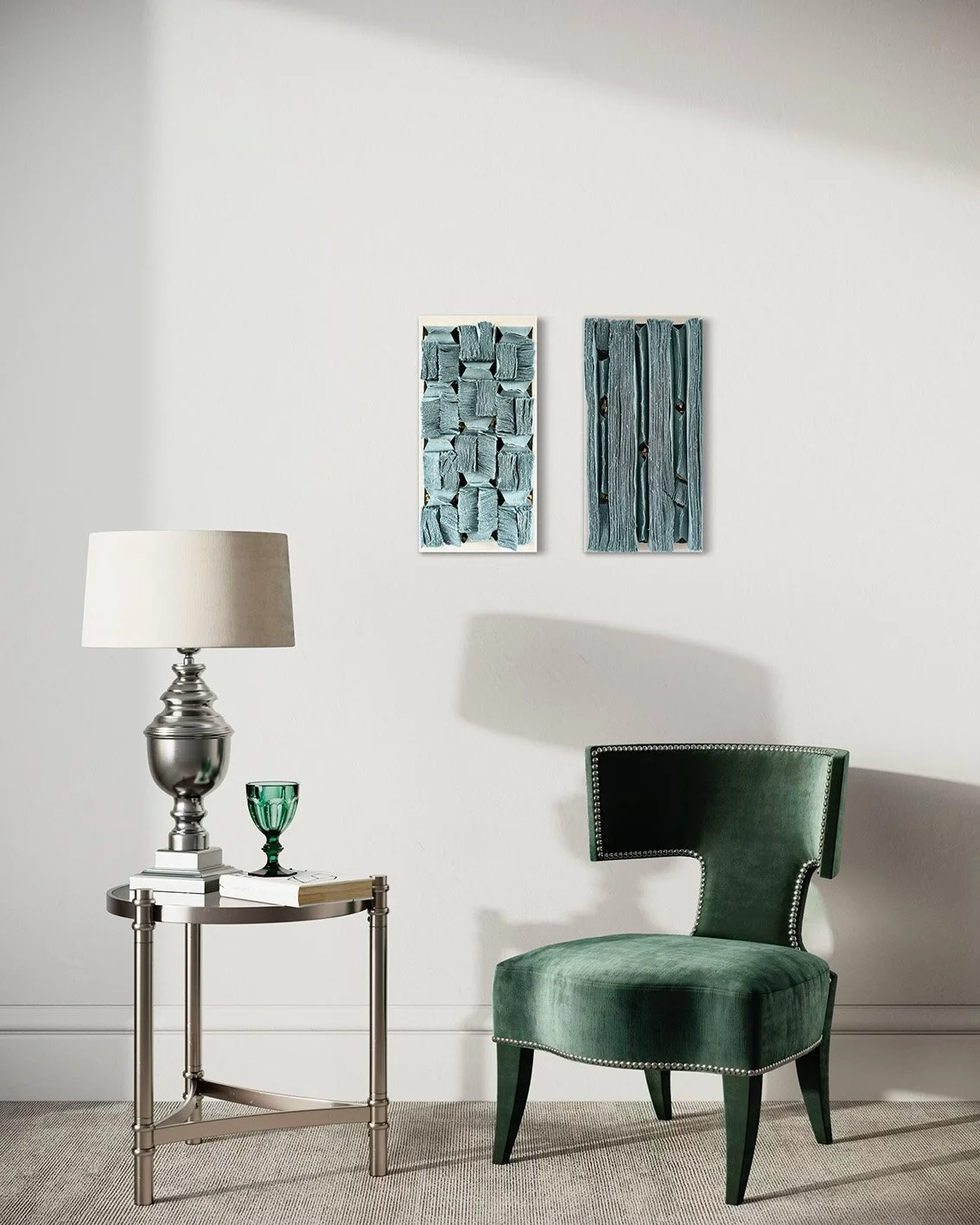 Een interieur met een witte muur, een tafeltje met een lamp, een groene glas, boeken, twee kunstwerken aan de muur, en een groene stoel.