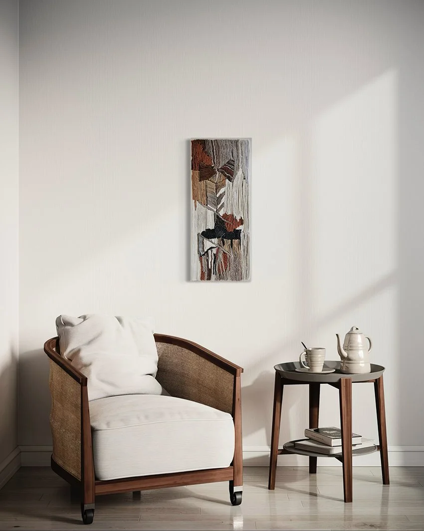 Een zithoek met een witte fauteuil en een kleine ronde tafel met boeken, een kan en kopjes, en een abstract kunstwerk aan de witte muur erachter.