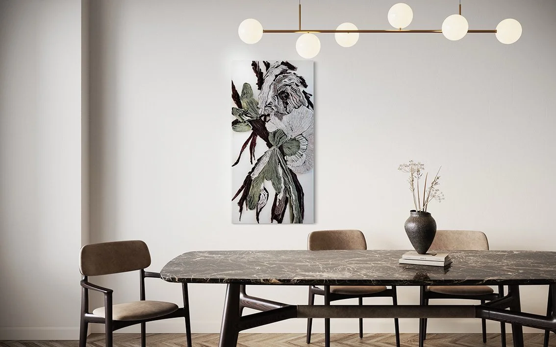 Moderne eettafel met zes stoelen, een grote Textiele wanddoek met een hertshoornvaren aan de muur, een vaas met bloemen en een lichte gordijn.