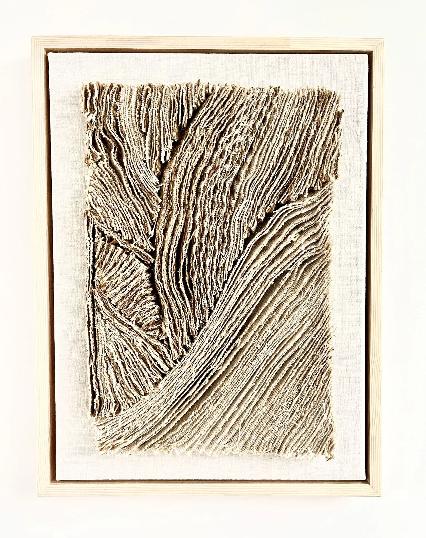 Gekreukeld tapijt in een houten lijst, gemaakt van beige, textuurrijk materiaal