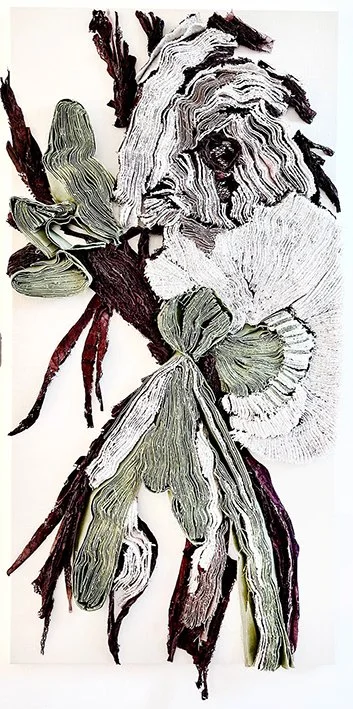 Een kunstwerk bestaande uit gedroogde en gesneden bladeren en takken die samen een bloemorganisch vormen.