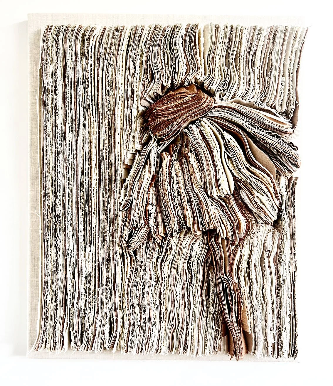 Een vierkant kunstwerk gemaakt van opgestapelde, gekleurde papierstroken die samen een grote strik vormen.