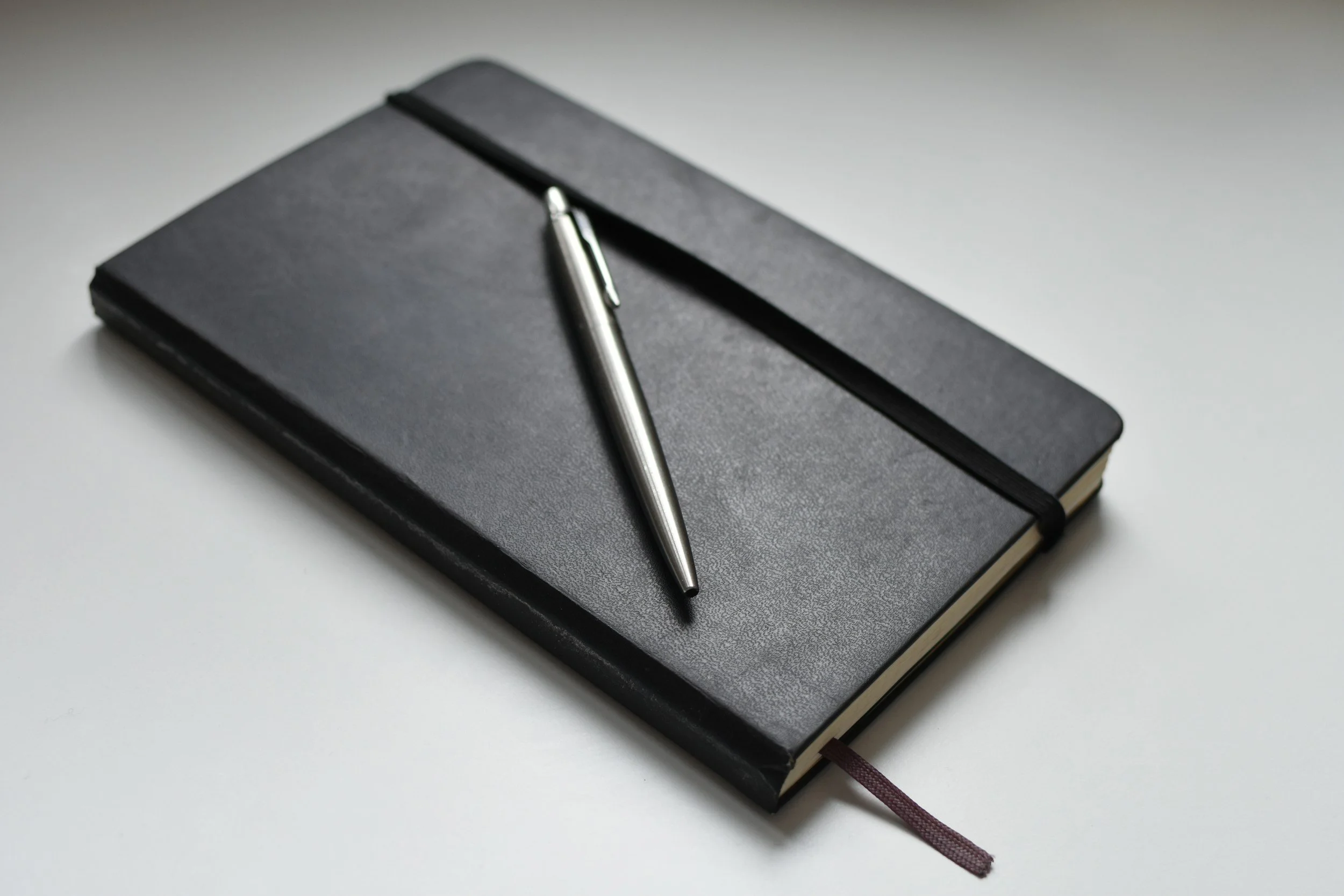 Elegant black leather notebook with a pen, conveying the strategic partnership offered by Latitude Narrative Strategy.