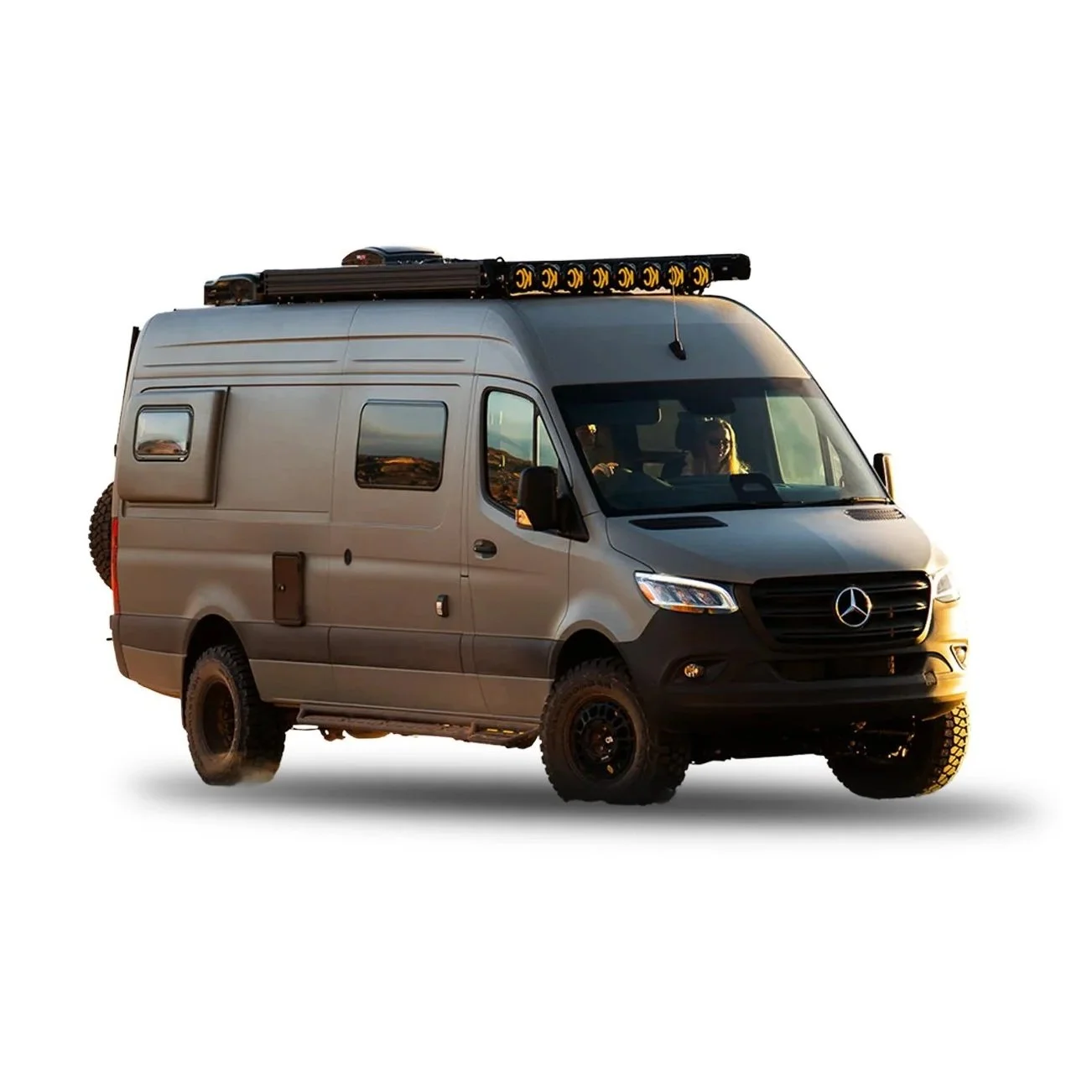 Silver Mercedes-Benz van with off-road tires, roof-mounted light bar, and side storage box, isolated on white background.